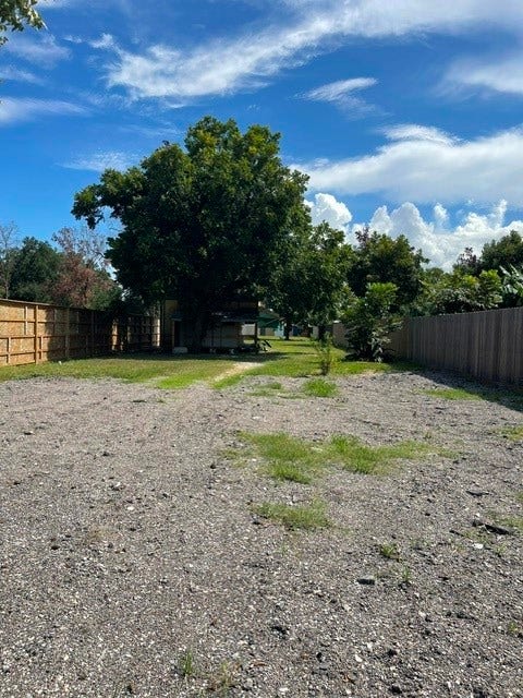 408 B Vista Road, Pasadena, TX 77504 Expansive lot with a mix of gravel and greenery, bordered by wooden fencing, perfect for creating your dream outdoor space.