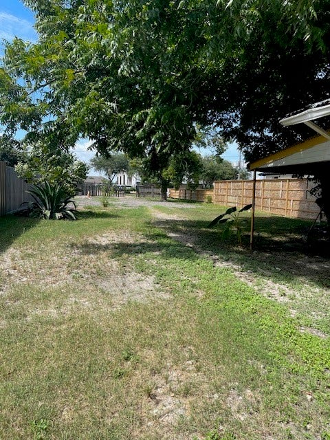 408 B Vista Road, Pasadena, TX 77504 Expansive backyard with mature trees providing ample shade, surrounded by a privacy fence for a serene outdoor retreat.