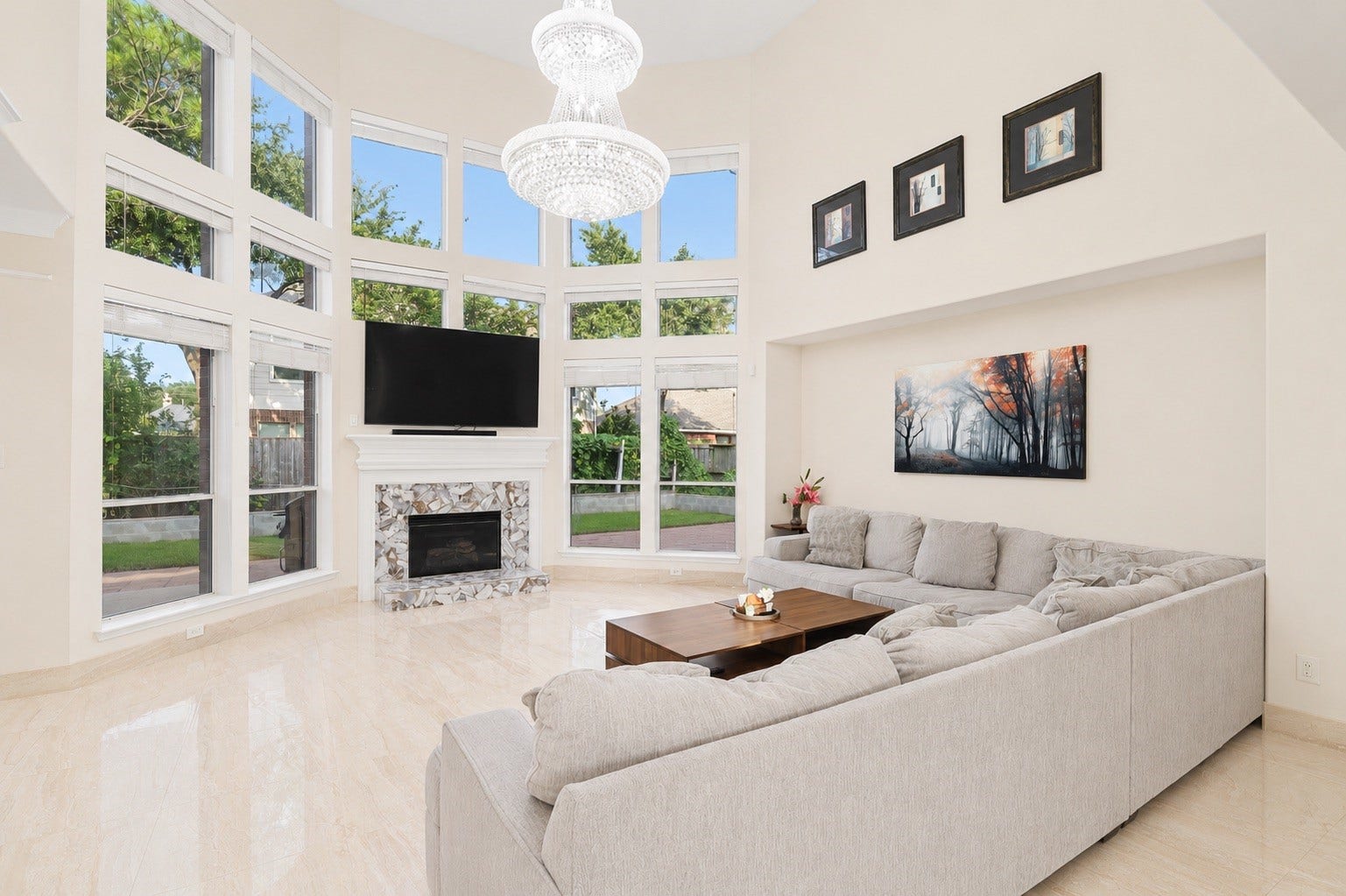 2614 Sunset Lake Drive, Sugar Land, TX 77478 Spacious living room with high ceilings and large windows providing abundant natural light. Features a modern chandelier, a cozy fireplace.