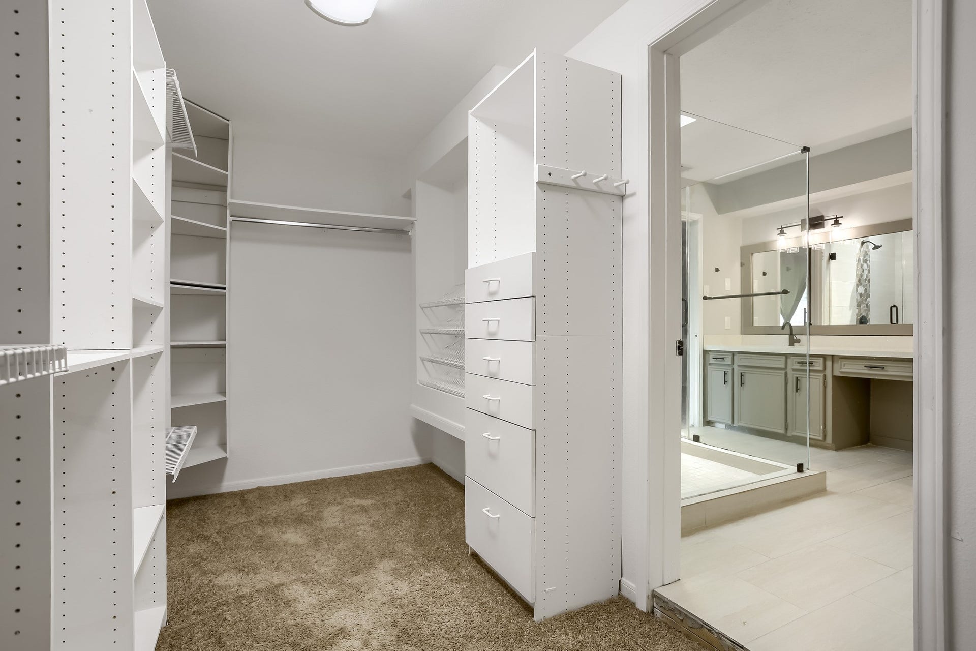 16505 Cornwall Street, Jersey Village, TX 77040 This photo showcases a spacious walk-in closet with ample shelving and hanging space, leading into a modern bathroom with dual sinks and a large mirror.