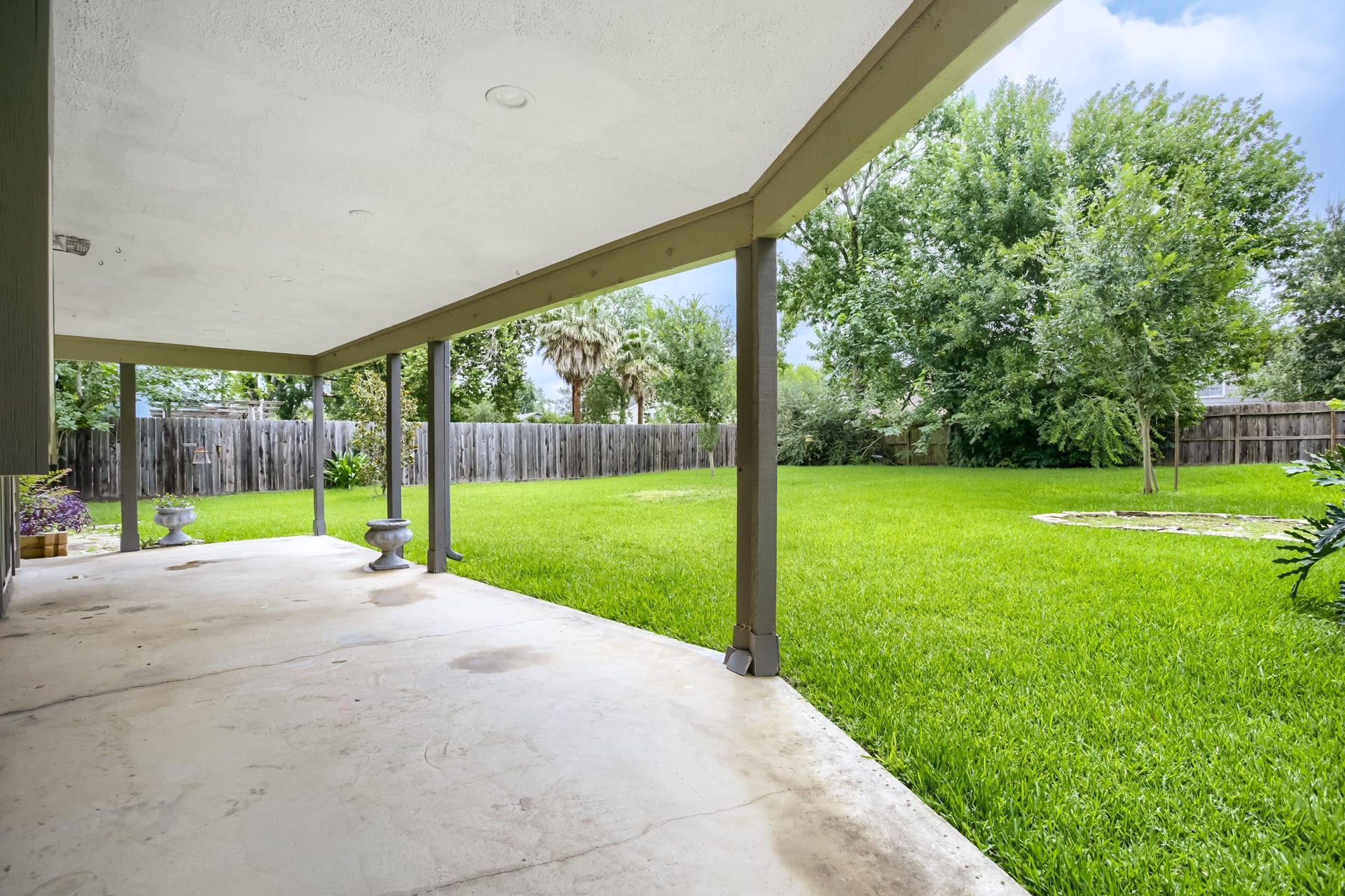 16505 Cornwall Street, Jersey Village, TX 77040 View of the spacious backyard with a covered patio, lush green lawn, and mature trees, offering a serene outdoor space perfect for relaxation and entertainment.