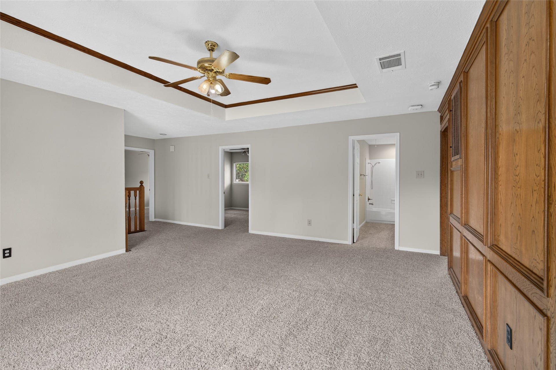 A tray ceiling, ceiling fan, carpeting, and warm wood paneling give this spacious room a comfortable atmosphere that can adapt to a variety of needs.