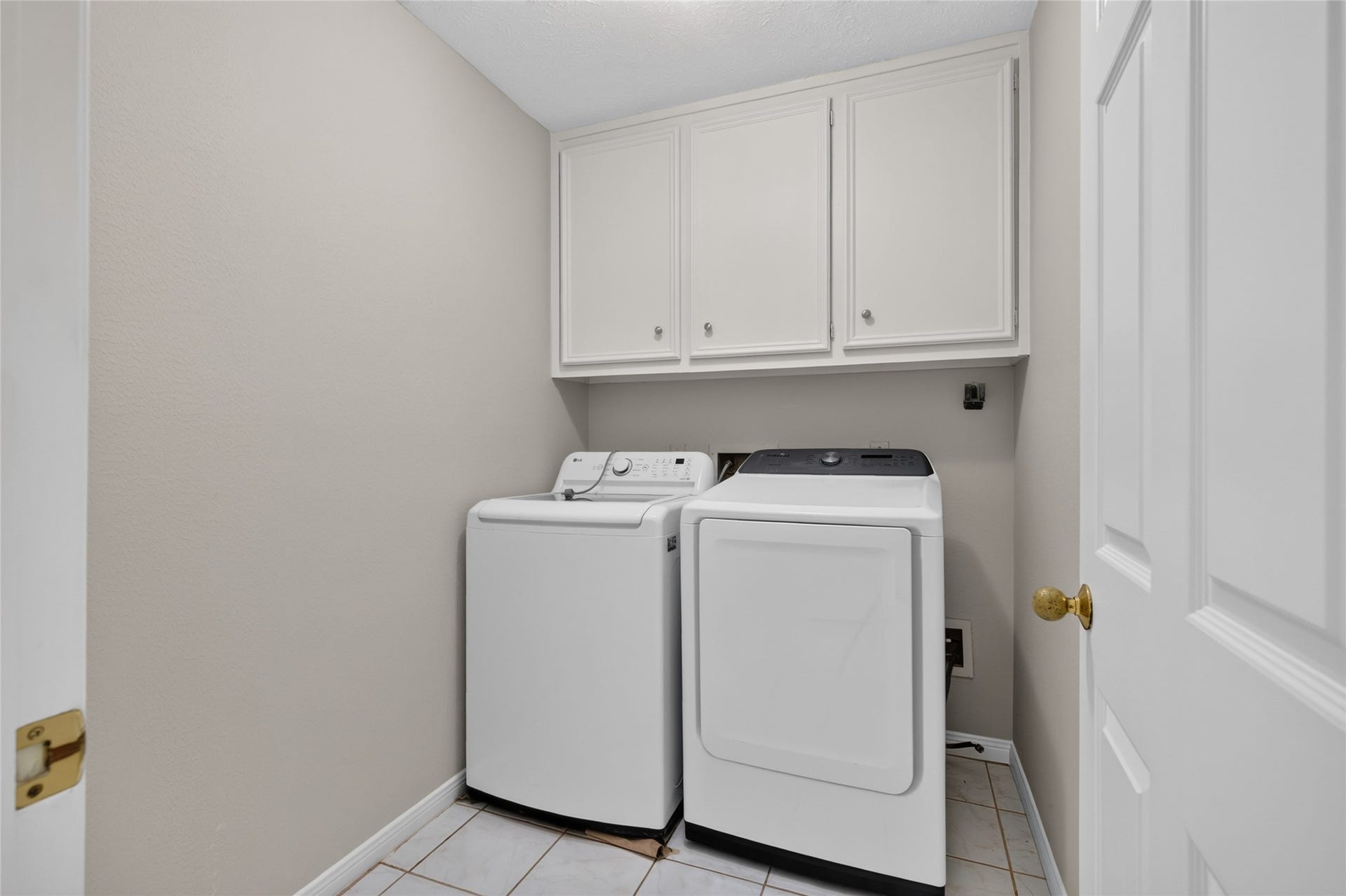 A dedicated laundry space with washer and dryer connections, overhead cabinetry, and an efficient layout keeps everyday household routines organized and convenient.