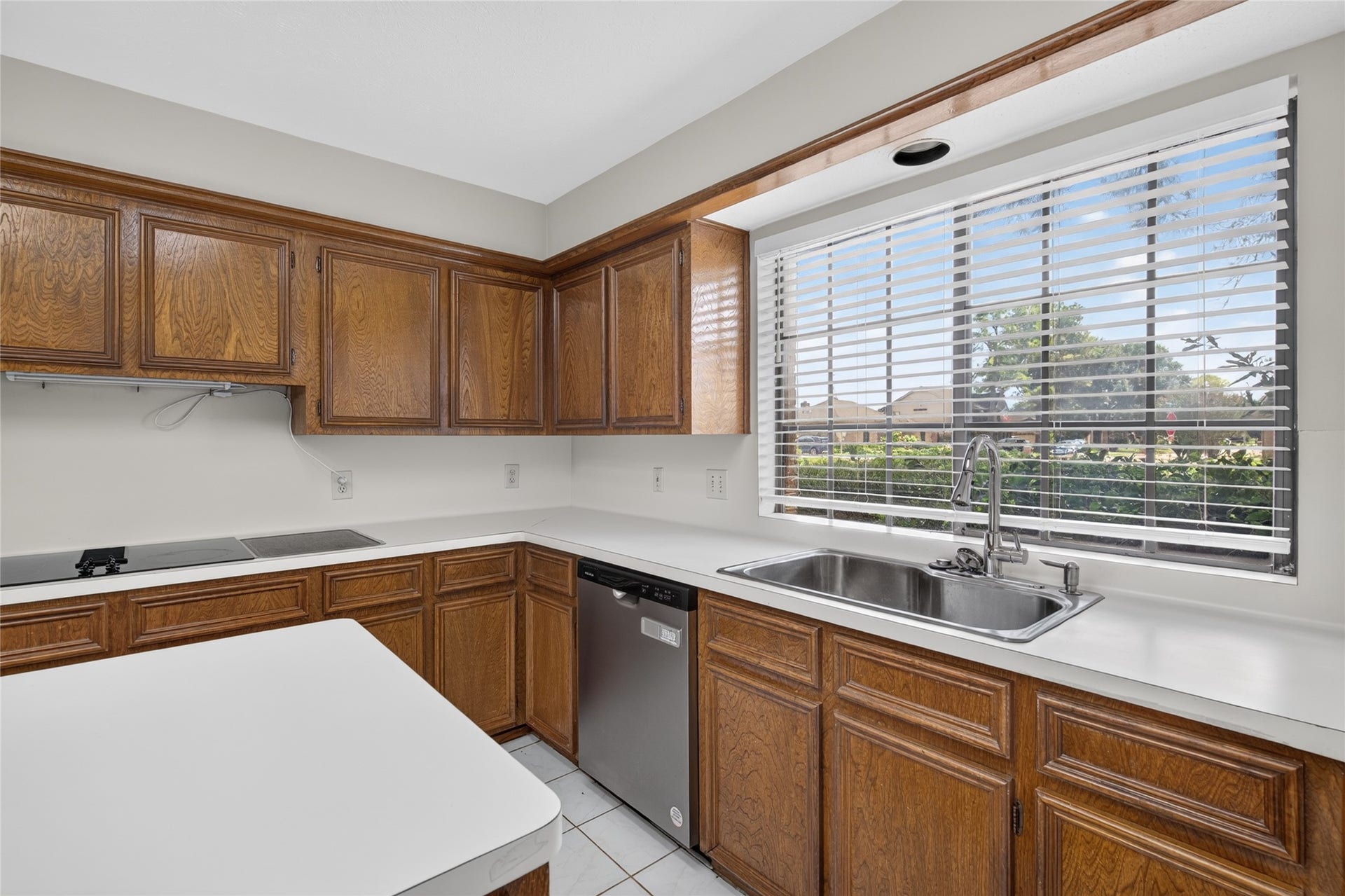 Natural light streams through the large window, highlighting the classic cabinetry and creating a bright workspace where cooking and daily routines feel effortless.