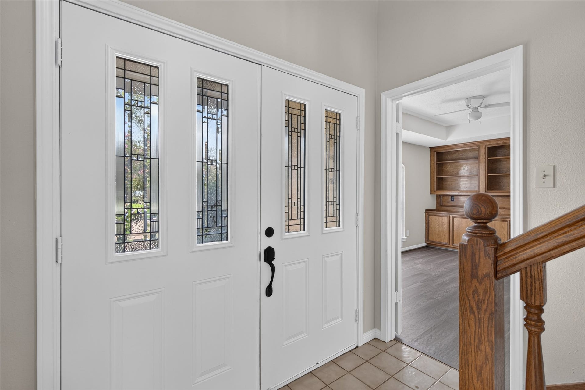 A distinctive glass-paneled front door opens into a welcoming foyer with built-in wood shelving, creating an attractive introduction to the home's thoughtful interior spaces.