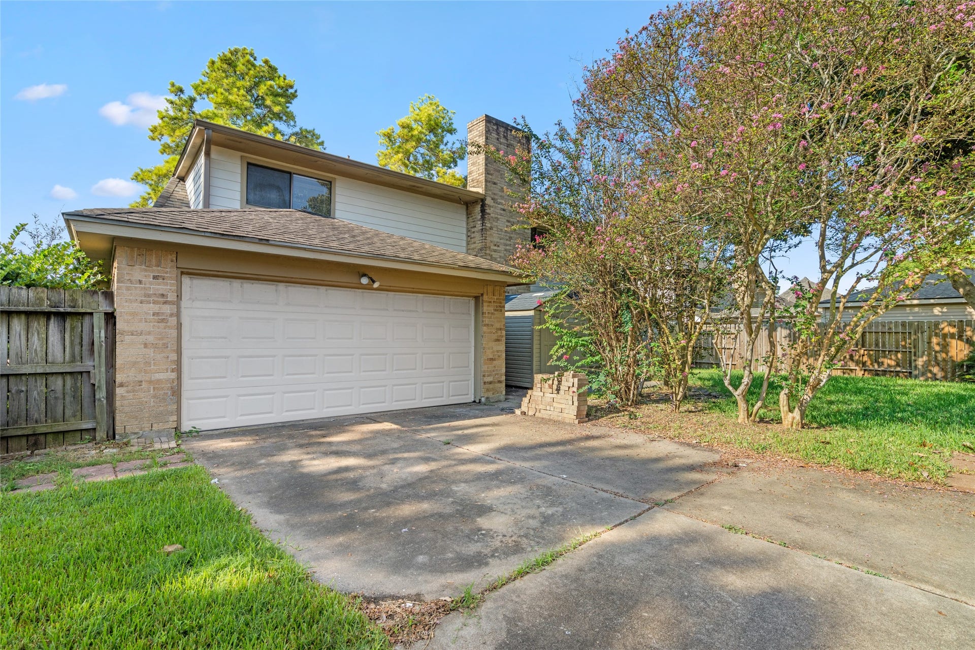 The two-story design, spacious garage, mature trees, and established yard create a private residential setting with practical outdoor appeal.