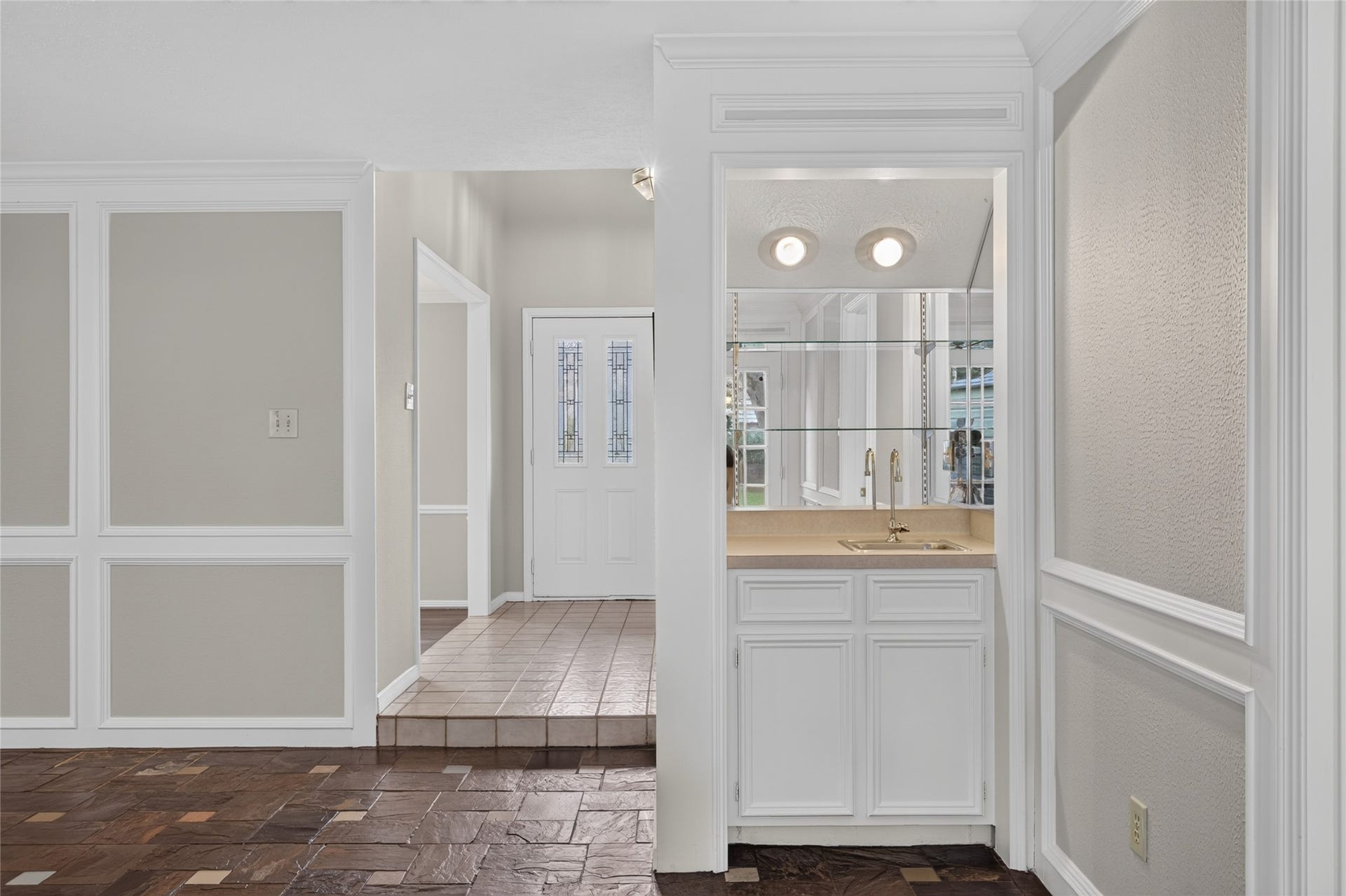 A charming built-in bar with mirrored backsplash and cabinetry creates a practical entertaining feature tucked naturally into the home's entry area.