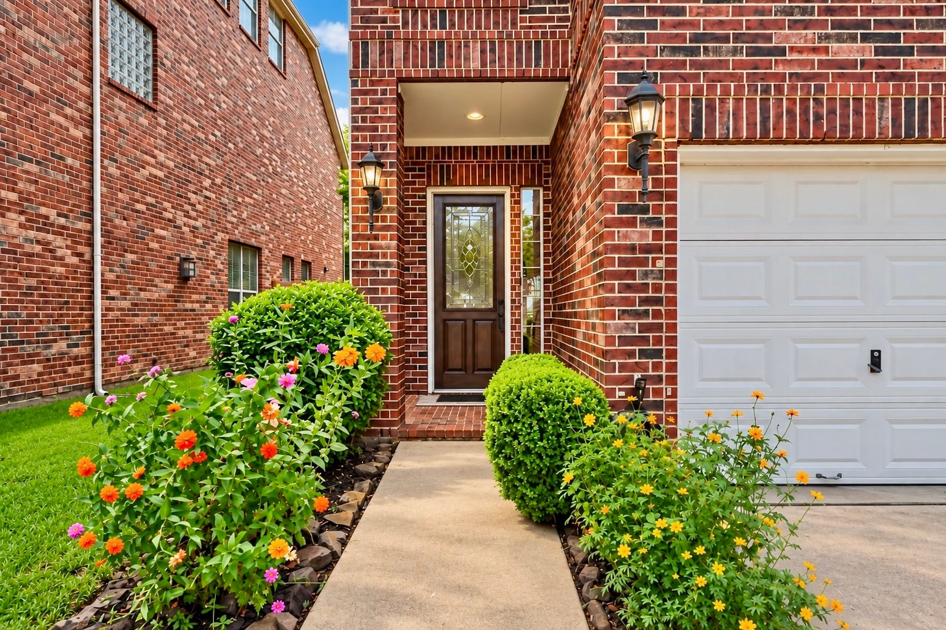 Charming front entry framed by mature landscaping and timeless brick architecture. Virtually enhanced photo.