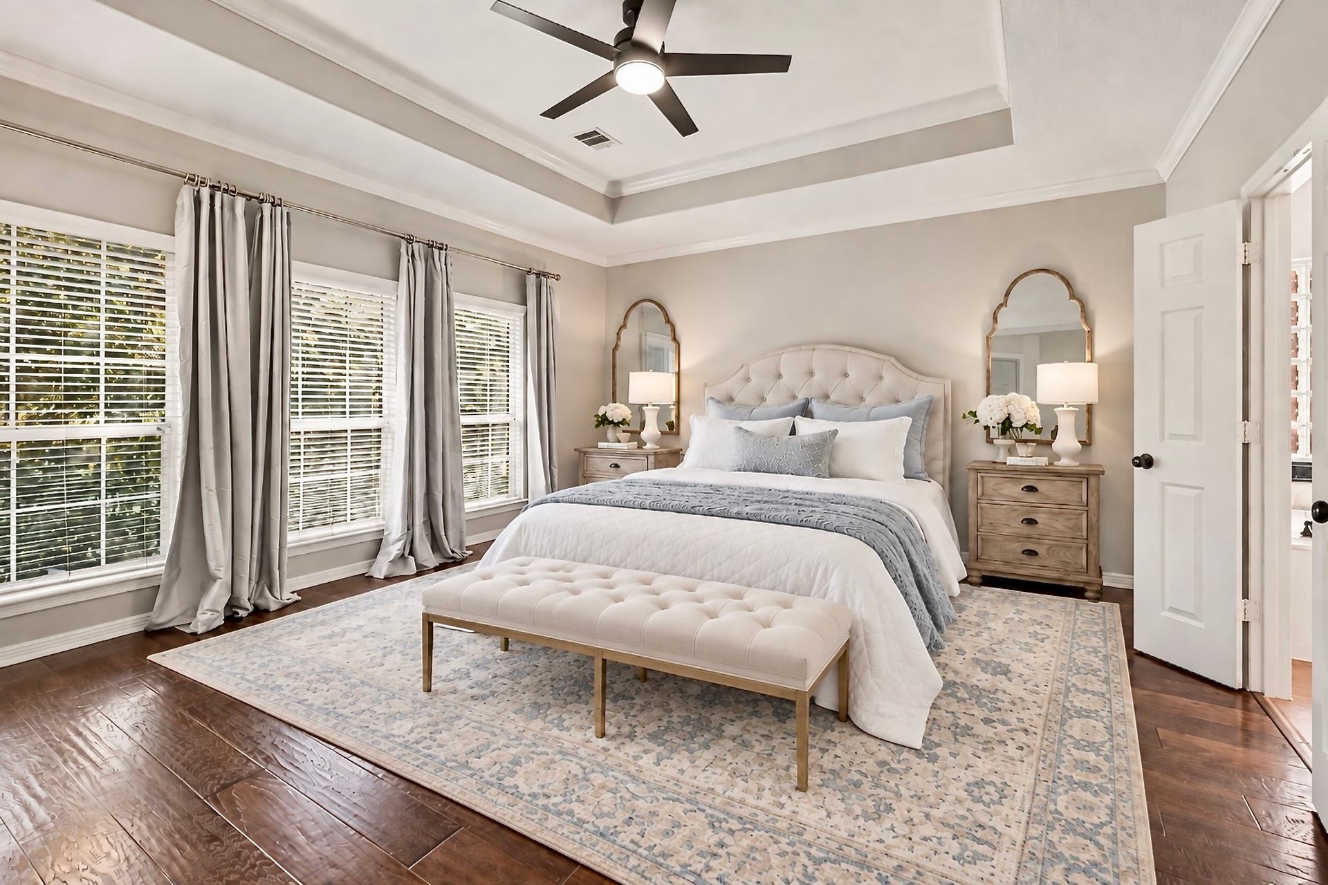 Spacious owners suite with tray ceiling, wood flooring, and soft natural light. Virtually staged