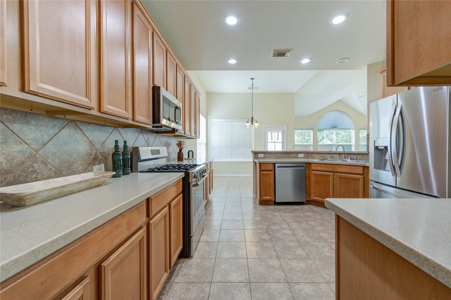 7811 Ravens Point Drive, Richmond, TX 77406 Well-appointed kitchen featuring ample cabinetry, STARON countertops, gas cooking, and an open-concept layout flowing seamlessly into the breakfast and living areas. Complete with updated stainless steel appliances.