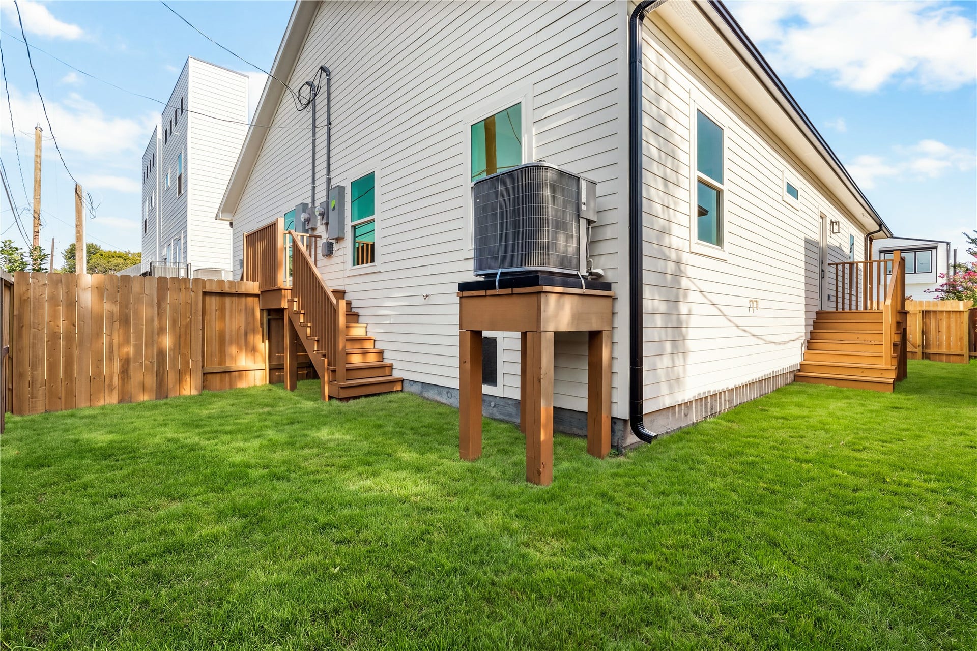5321 Rue Street, Houston, TX 77033 Fully fenced side yard vibrant green lawn, elevated exterior steps, and clean siding detailing surrounding the home.