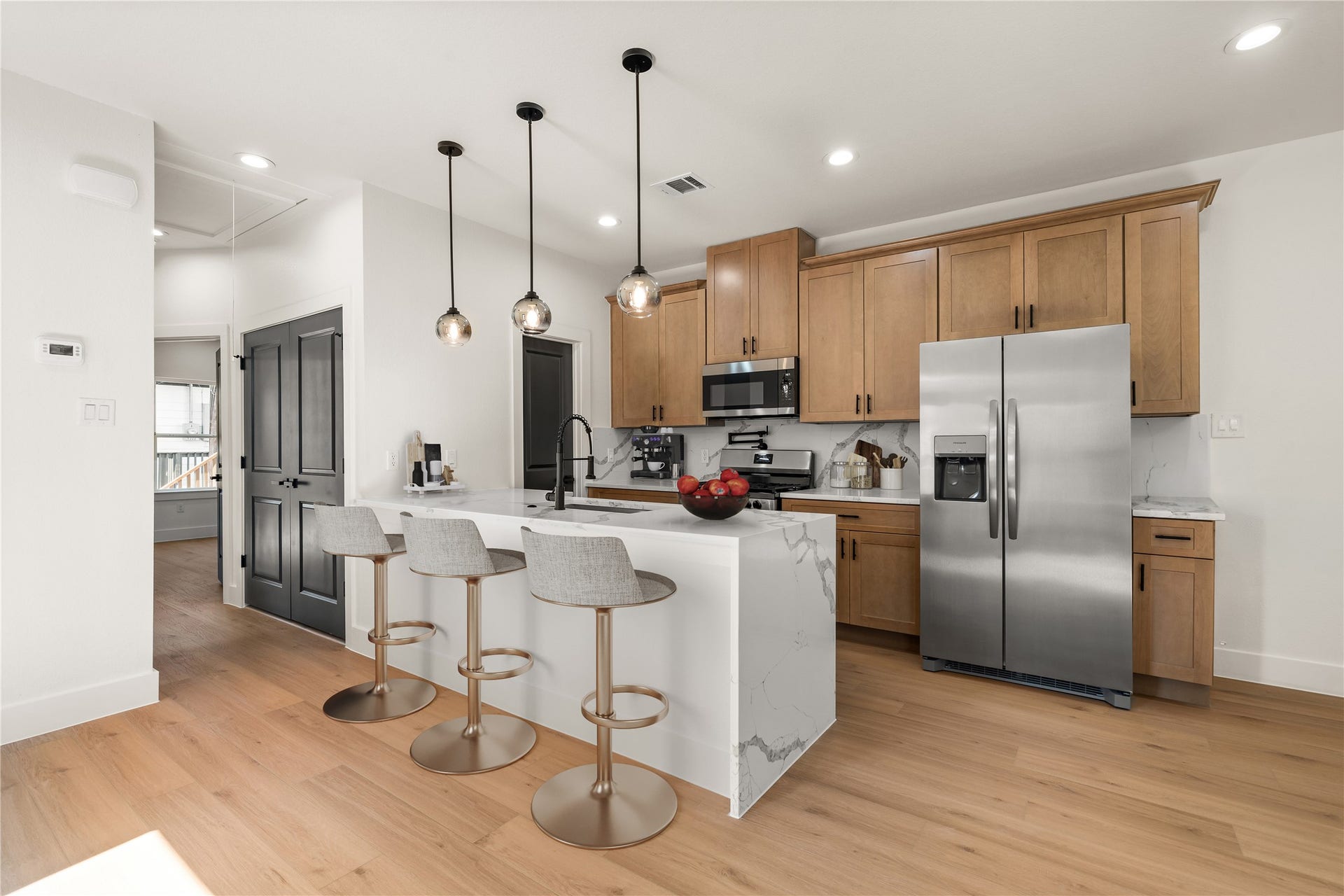 5321 Rue Street, Houston, TX 77033 Waterfall quartz island with seating for three, stainless appliances, and wood cabinets stacked high. Virtually staged.