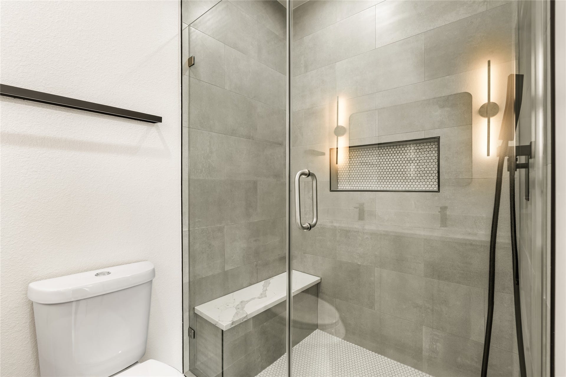 5321 Rue Street, Houston, TX 77033 Spa-inspired walk-in shower full-height large format tile, mosaic niche detail, frameless glass enclosure, and built-in quartz bench seat.