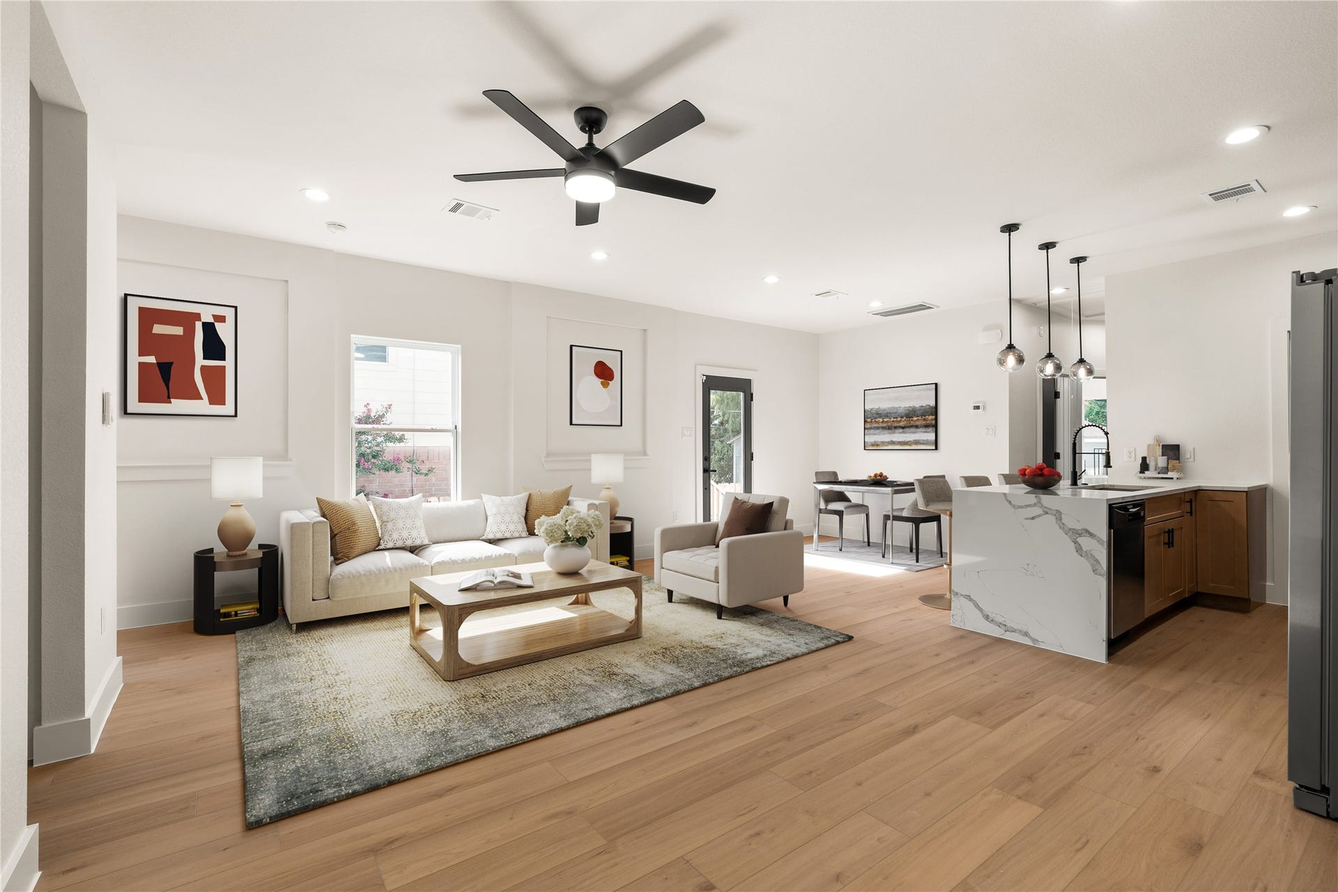 5321 Rue Street, Houston, TX 77033 Living room under a matte black ceiling fan, waterfall island and dining nook just steps away. Virtually staged.