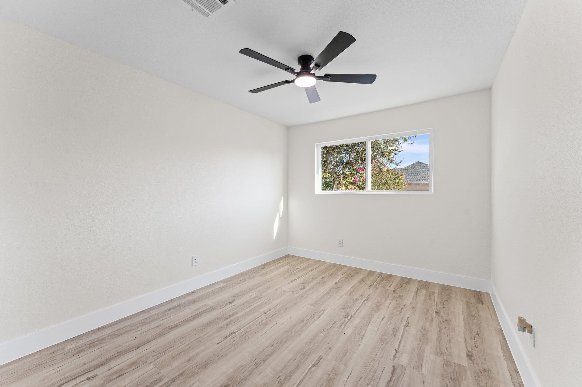 One of the secondary bedrooms, with updated flooring, windows, and a new fan.