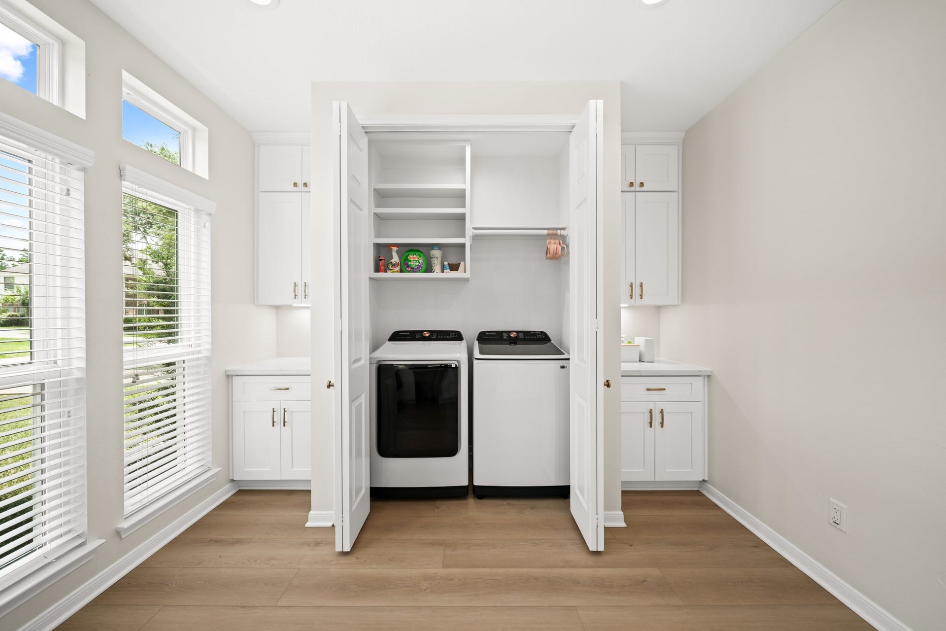 403 Trail Head Street, Friendswood, TX 77546 Thoughtfully concealed behind custom cabinetry, the laundry area offers added shelving and exceptional organization while maintaining a clean, streamlined aesthetic throughout the space.