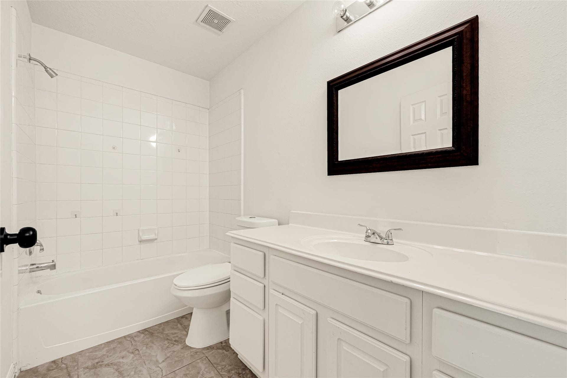 7102 Hollow Field Lane, Cypress, TX 77433 Well-appointed full bathroom offering a spacious vanity with extended counter space, a dark wood-framed mirror, and a clean, classic tiled shower/tub combo.