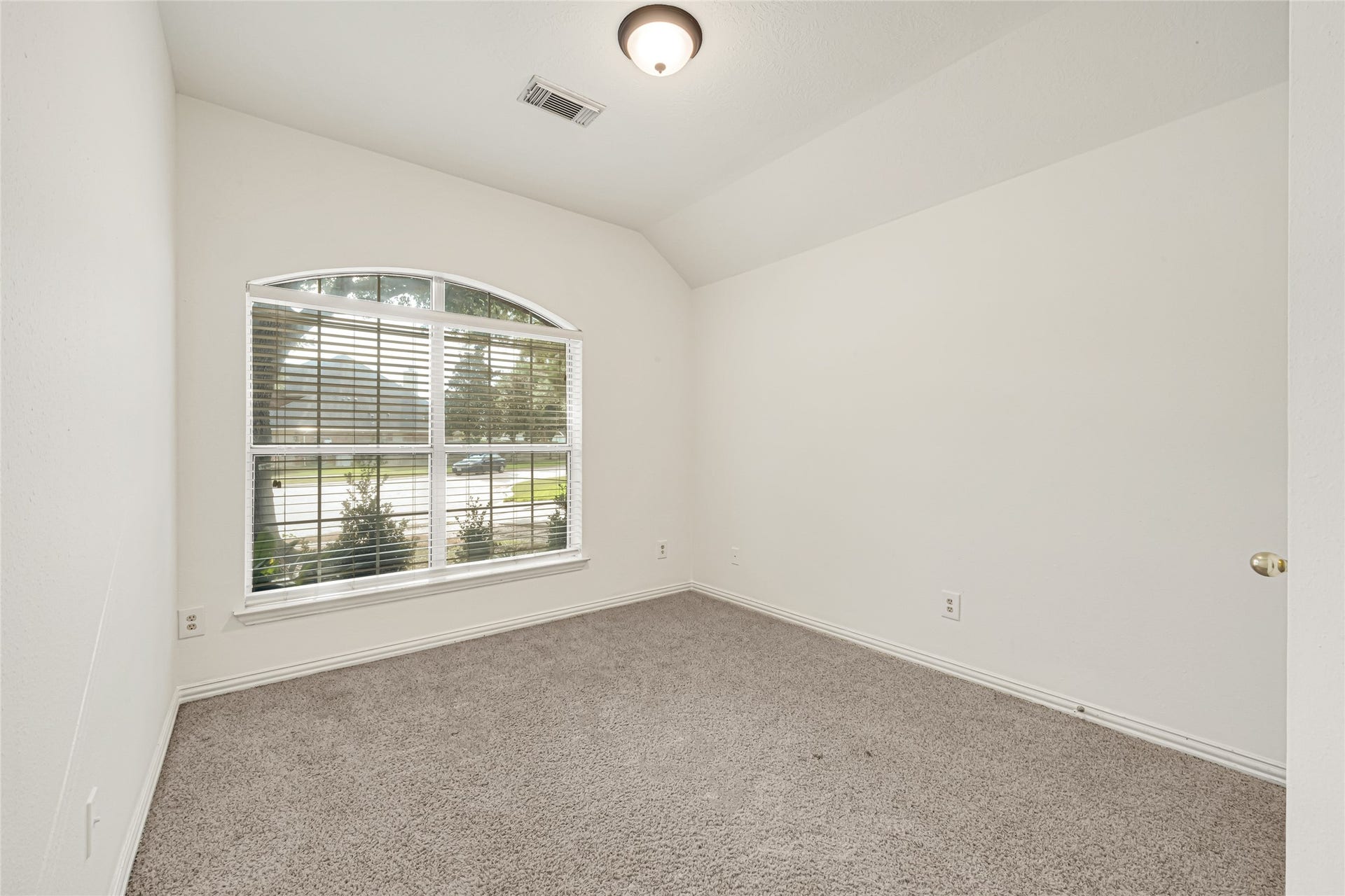 7102 Hollow Field Lane, Cypress, TX 77433 Bright secondary bedroom featuring plush carpeting, crisp neutral paint, and an elegant arched window that fills the space with natural light.