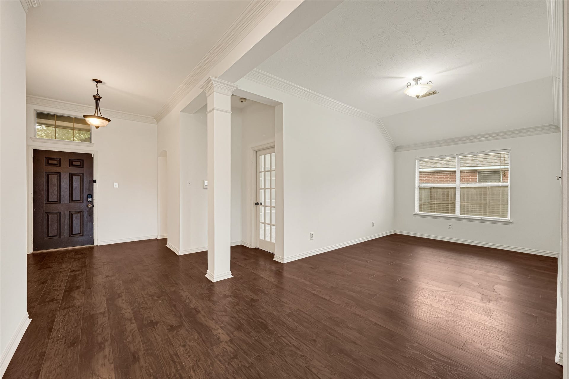 7102 Hollow Field Lane, Cypress, TX 77433 A view from the living room looking back toward the entry, highlighting the elegant architectural columns and an abundance of natural light.
