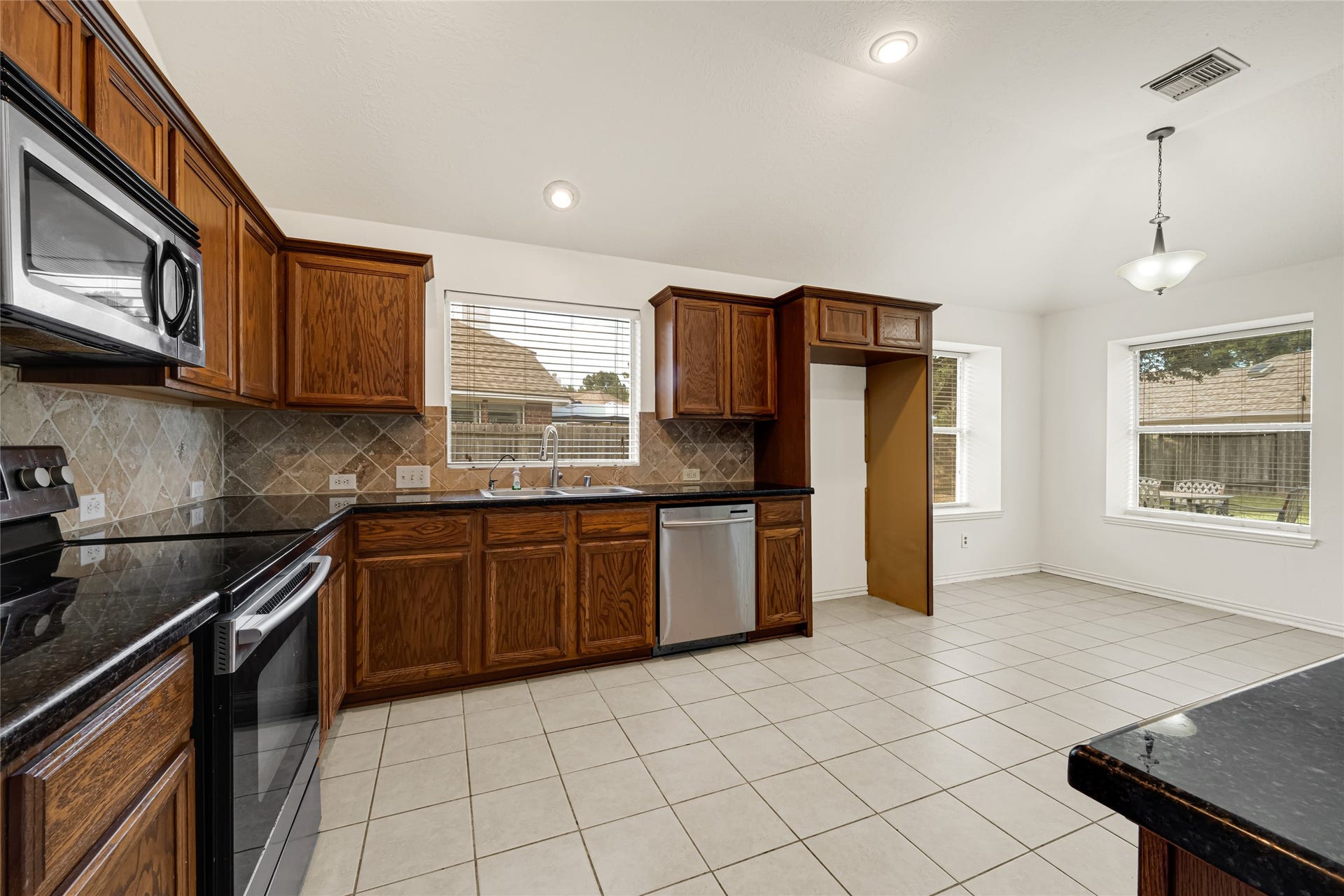 7102 Hollow Field Lane, Cypress, TX 77433 A closer look at the kitchen layout highlighting the abundant countertop workspace, tile backsplash, and views out to the backyard from the sink.