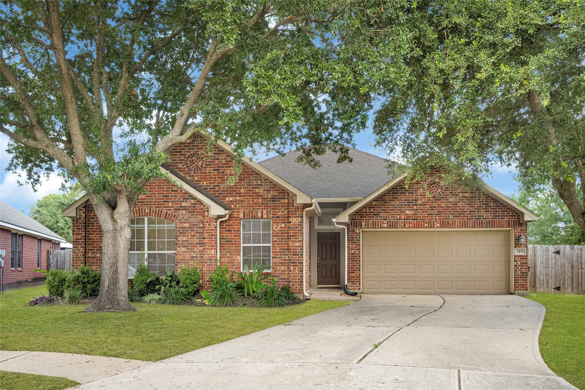 7102 Hollow Field Lane, Cypress, TX 77433 Beautiful daytime curb appeal showcasing a classic red brick exterior, mature shade trees, elegant landscaping, and a spacious two-car garage.
