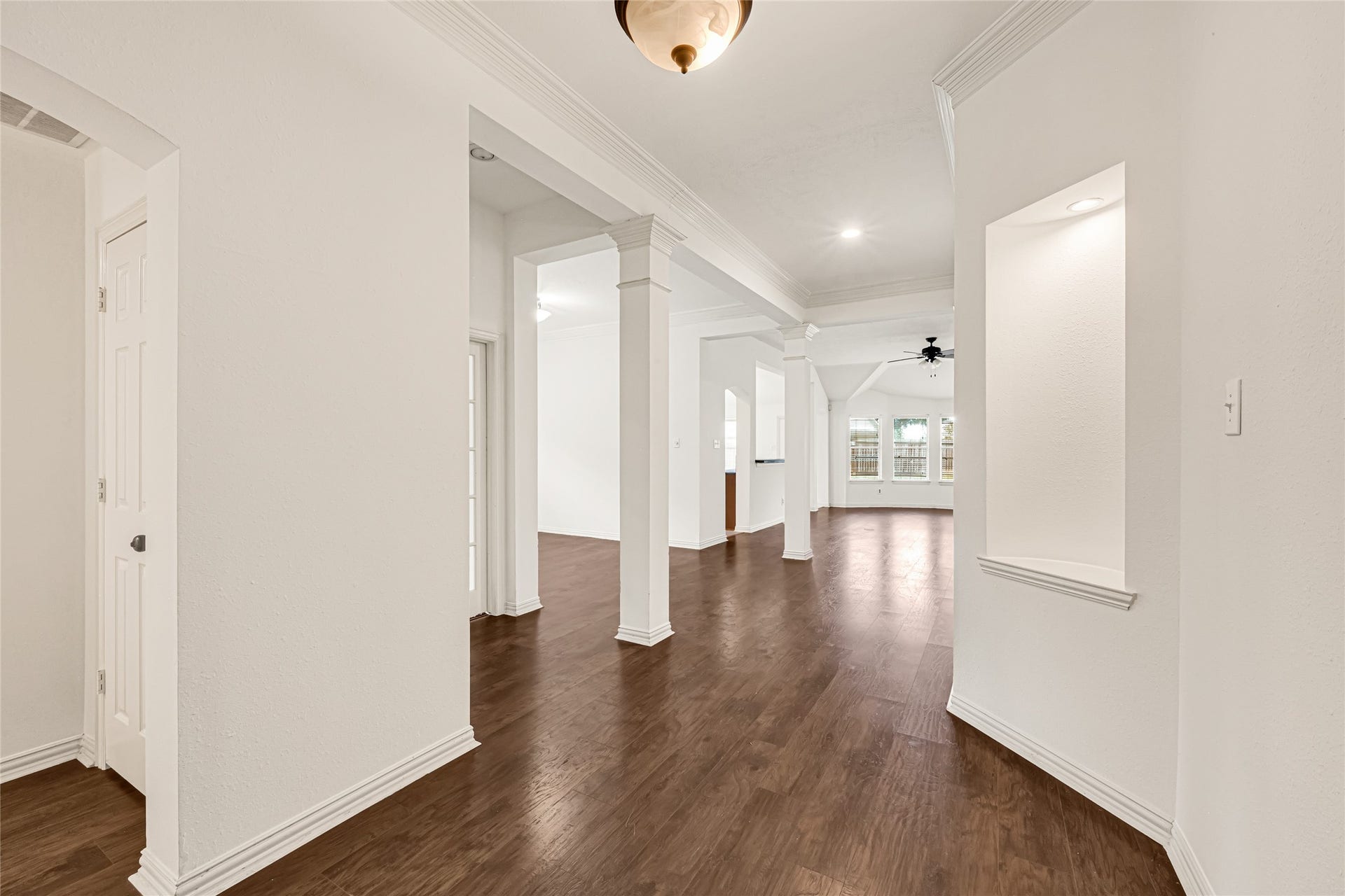 7102 Hollow Field Lane, Cypress, TX 77433 Bright and airy foyer boasting a rich wood-look flooring transition, neutral wall tones, and architectural columns guiding you into the home.