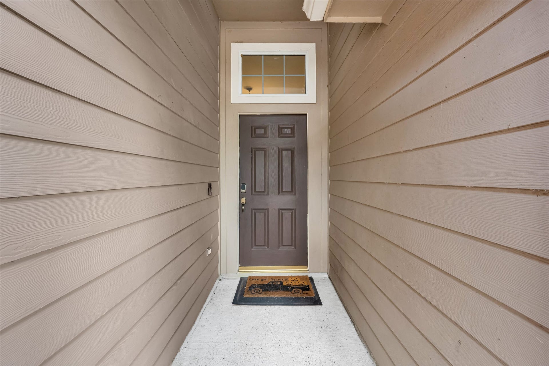 7102 Hollow Field Lane, Cypress, TX 77433 Private entryway featuring modern neutral siding, a classic paneled front door, and a bright transom window above.