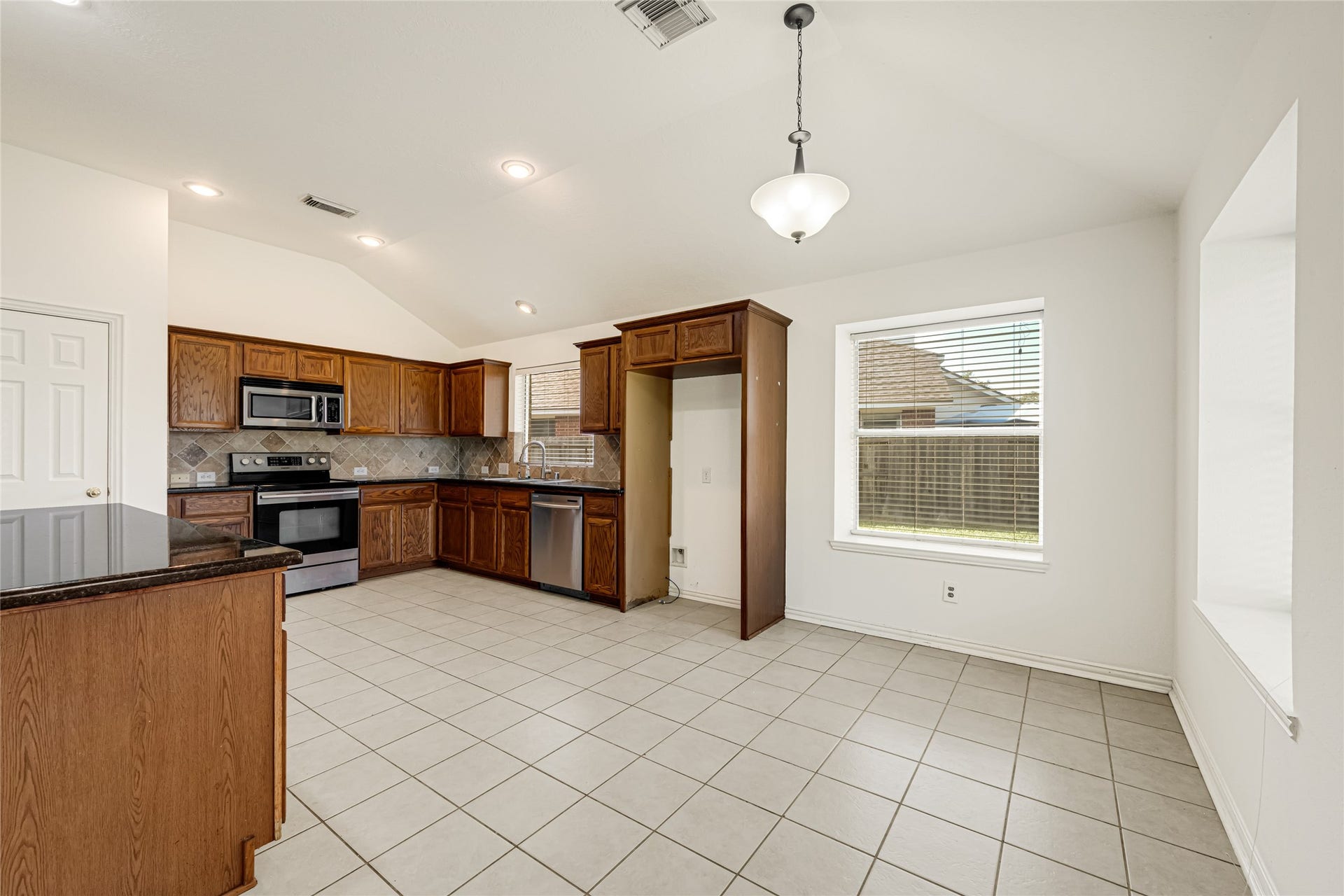 7102 Hollow Field Lane, Cypress, TX 77433 Spacious kitchen and casual dining area complete with traditional oak cabinetry, neutral tile flooring, a dedicated pantry closet, and vaulted ceilings.