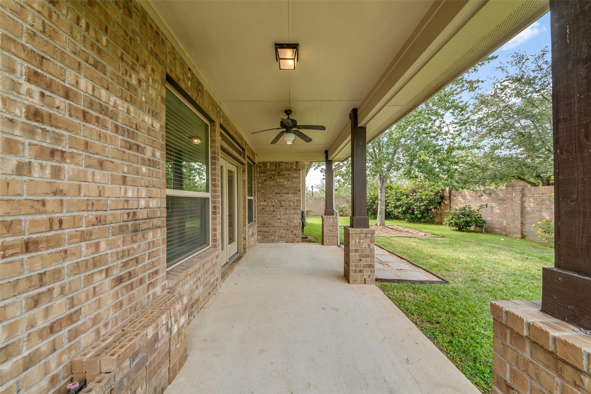 12218 Rampy Green Drive, Tomball, TX 77377 Spacious covered patio with a ceiling fan and brick accents.