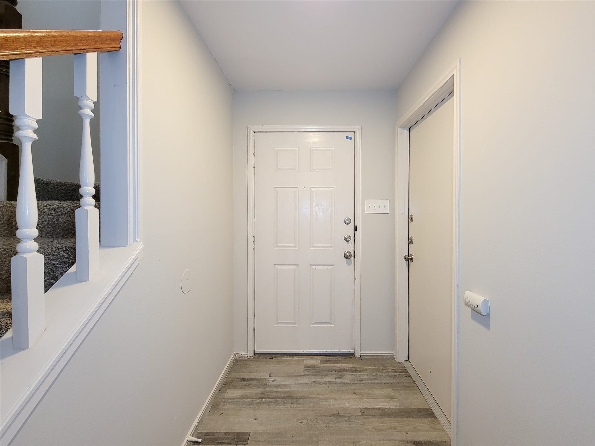 80 Fallenstone Drive, The Woodlands, TX 77381 Inviting entryway with a modern white door, stylish wood-look flooring, and a staircase featuring classic balustrades.