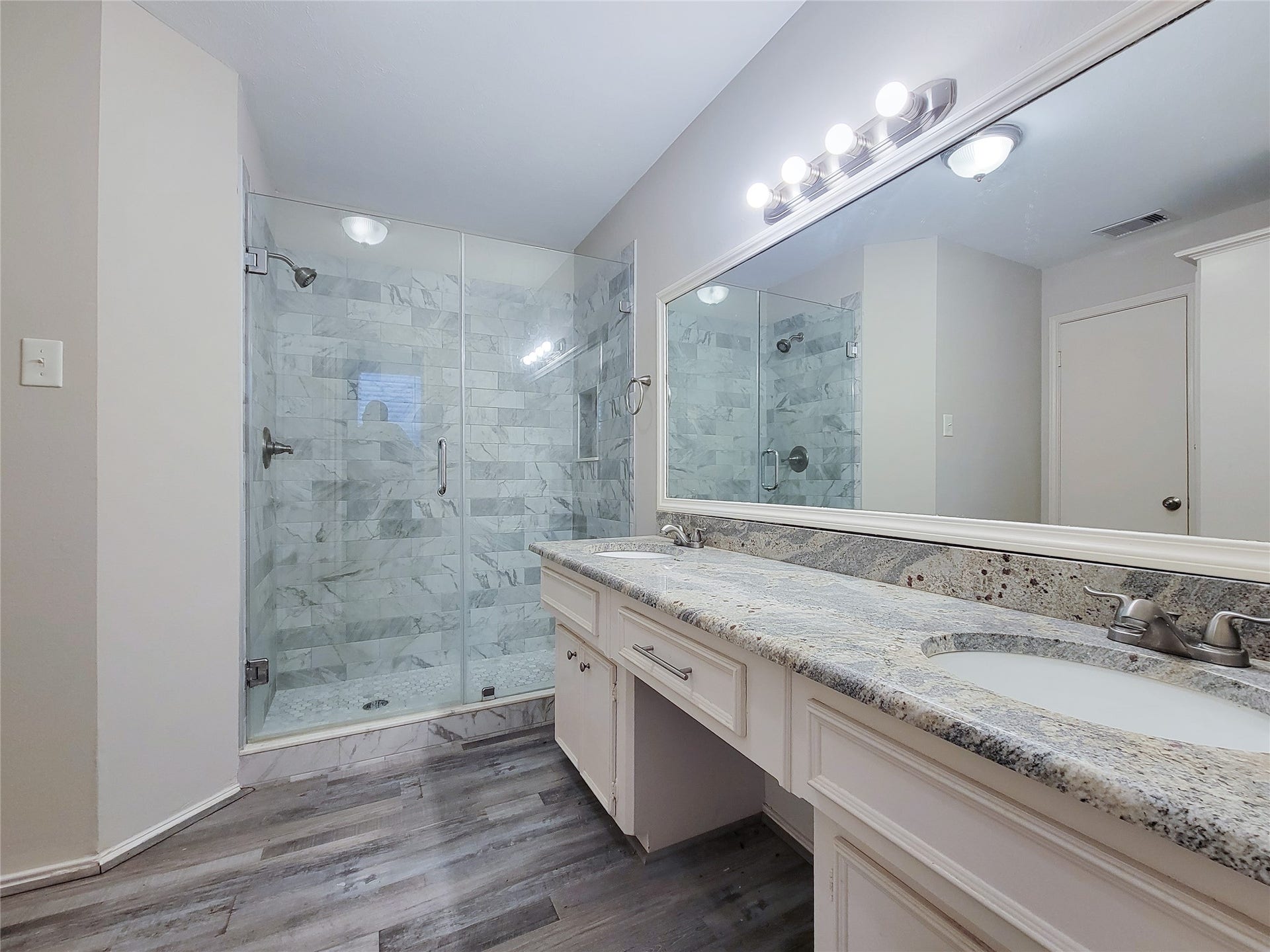 80 Fallenstone Drive, The Woodlands, TX 77381 Elegant bathroom featuring a spacious glass-enclosed shower with stylish tiled walls, a sleek dual-sink vanity with granite countertops, and modern lighting fixtures.