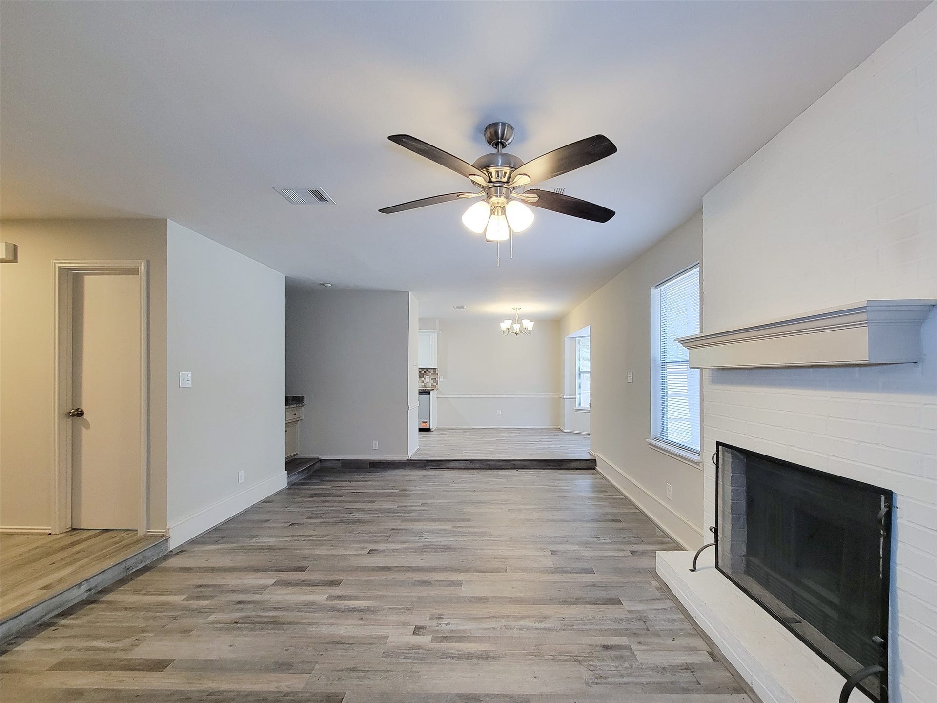 80 Fallenstone Drive, The Woodlands, TX 77381 Spacious living area with elegant wood flooring, a cozy fireplace, and ample natural light from large windows, seamlessly leading into the dining space.