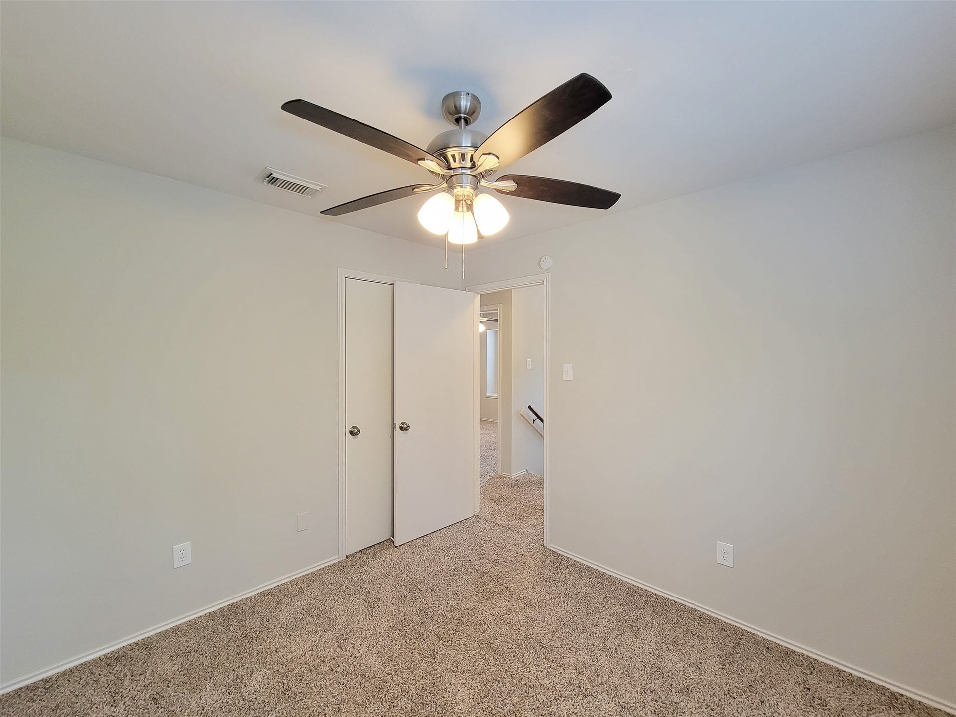 80 Fallenstone Drive, The Woodlands, TX 77381 Bright and inviting bedroom with plush carpeting, featuring a modern ceiling fan and ample natural light.