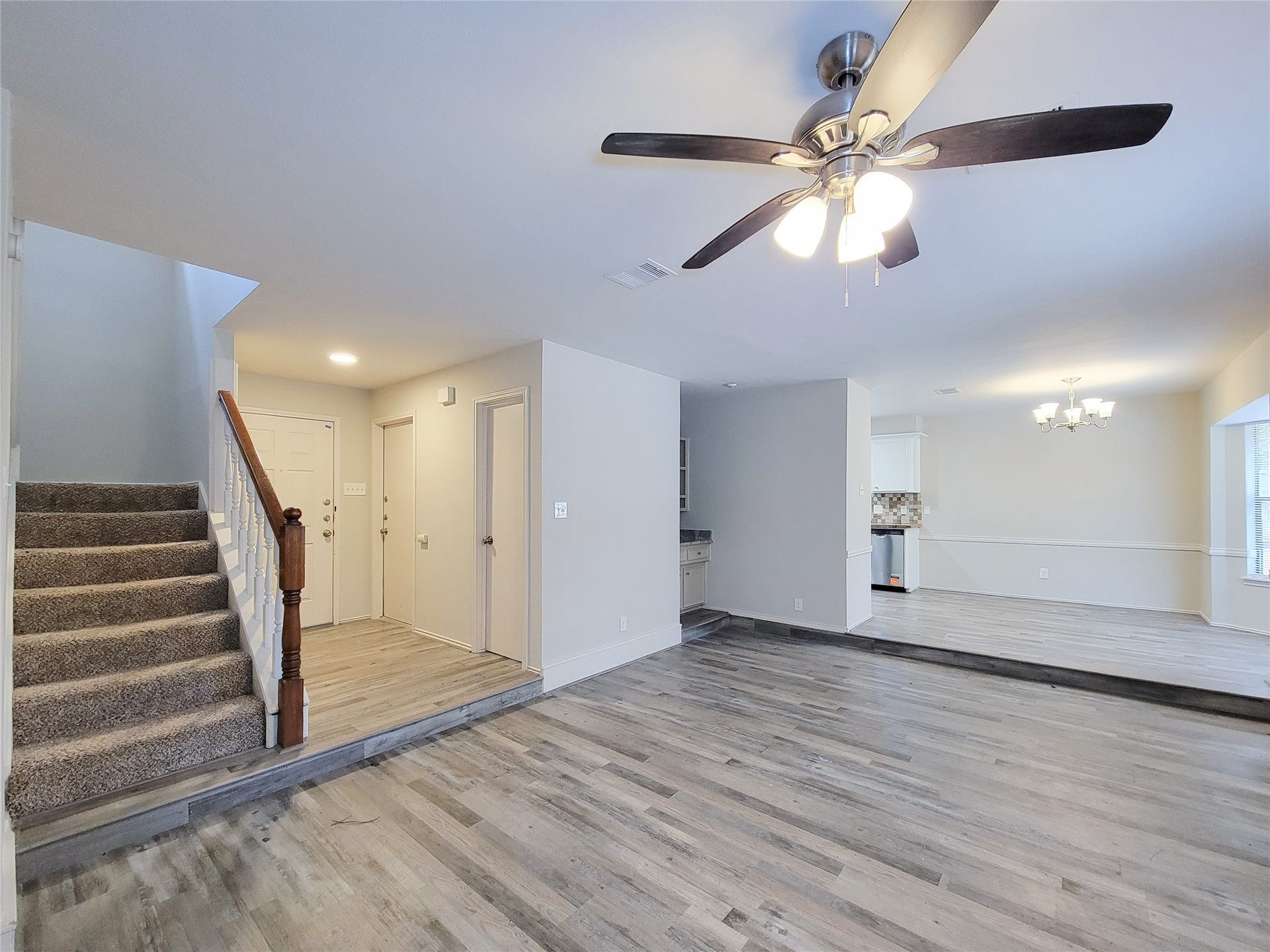 80 Fallenstone Drive, The Woodlands, TX 77381 Spacious open-plan living area with elegant laminate flooring, modern ceiling fan, and a cozy carpeted staircase leading to the upper level.