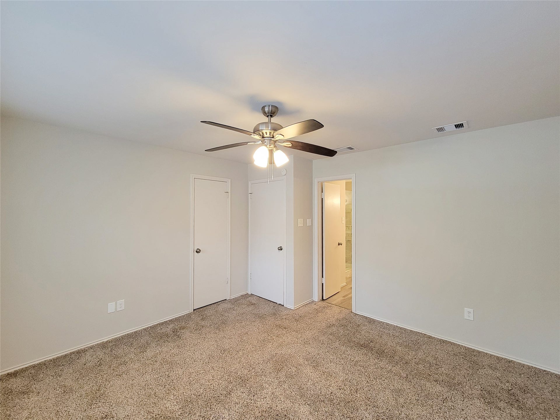 80 Fallenstone Drive, The Woodlands, TX 77381 Spacious bedroom featuring plush carpeting, a ceiling fan for comfort, and a convenient en-suite bathroom.