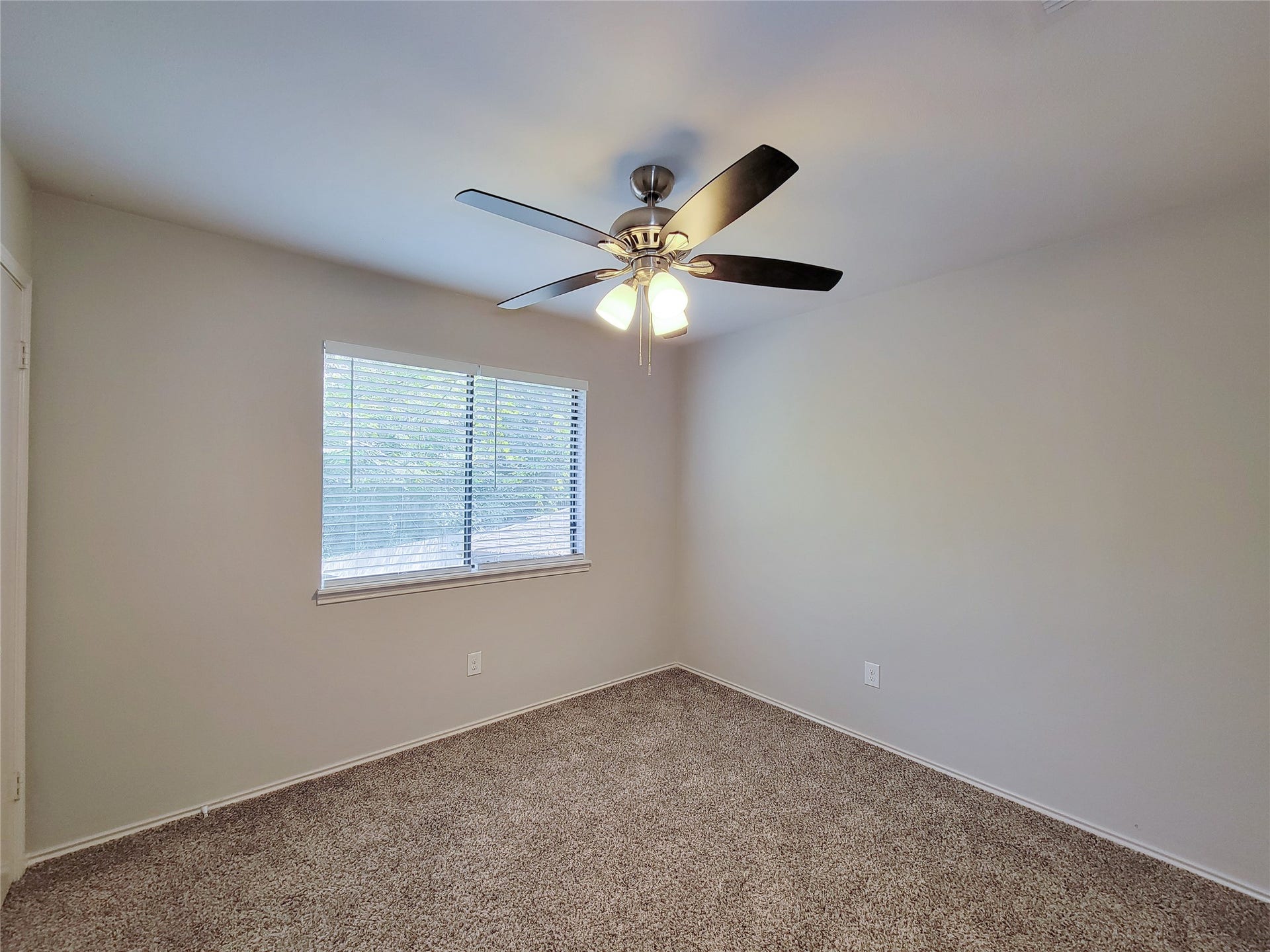 80 Fallenstone Drive, The Woodlands, TX 77381 Cozy bedroom with plush carpet, neutral walls, and a ceiling fan, offering natural light through a well-sized window with blinds.