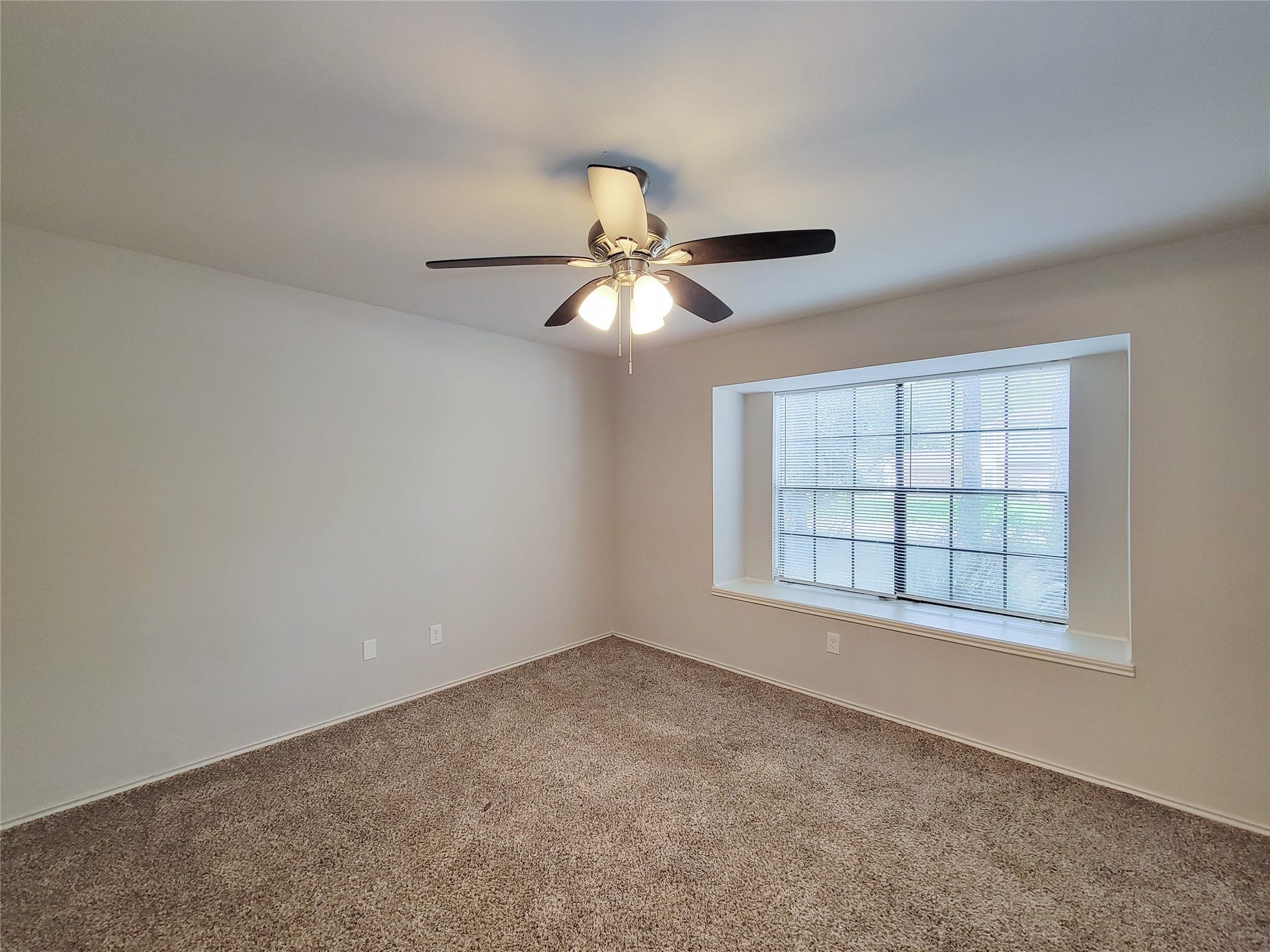 80 Fallenstone Drive, The Woodlands, TX 77381 Spacious room featuring a large bay window, plush carpeting, and a ceiling fan for comfort and style.