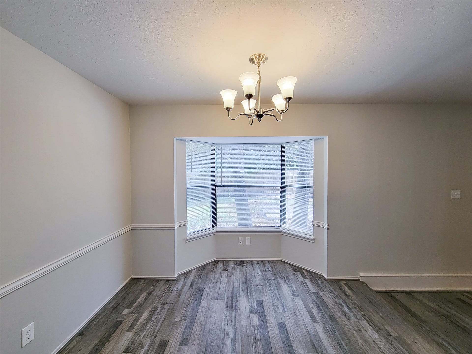 80 Fallenstone Drive, The Woodlands, TX 77381 Bright dining area with a bay window, elegant chandelier, and stylish wood flooring.