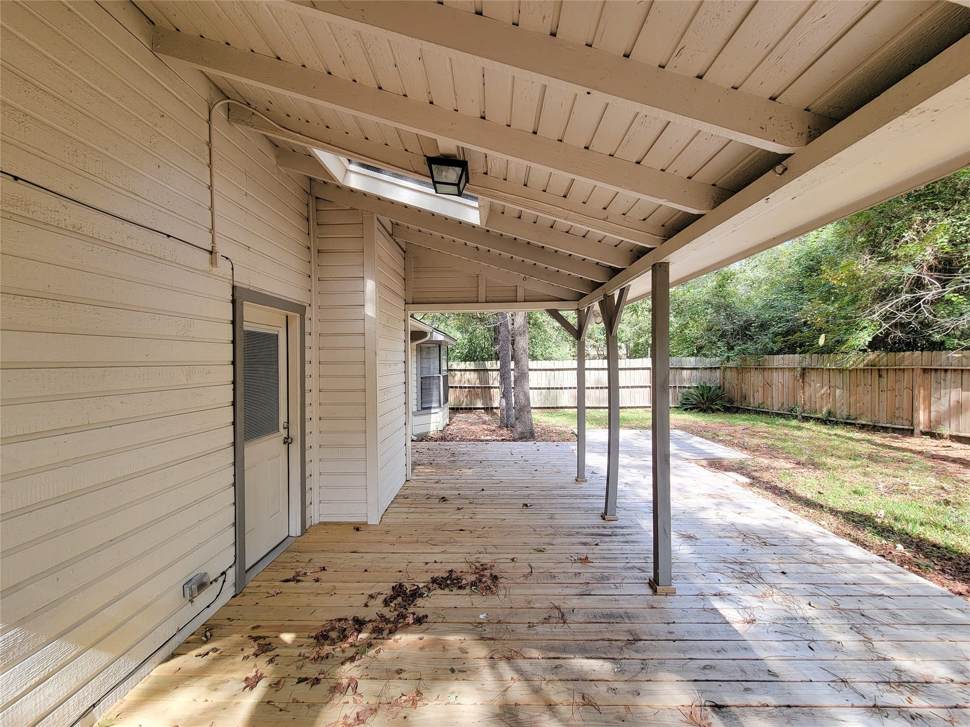 80 Fallenstone Drive, The Woodlands, TX 77381 Spacious covered patio with wooden decking, perfect for outdoor relaxation, overlooking a private fenced backyard with lush greenery.