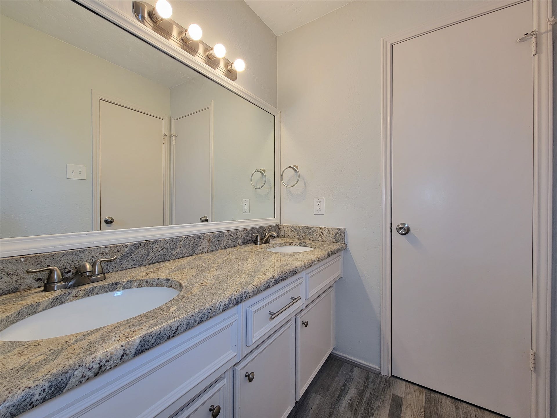 80 Fallenstone Drive, The Woodlands, TX 77381 Elegant bathroom featuring a spacious dual-sink vanity with sleek granite countertops, modern fixtures, and a large mirror, all set against stylish flooring.