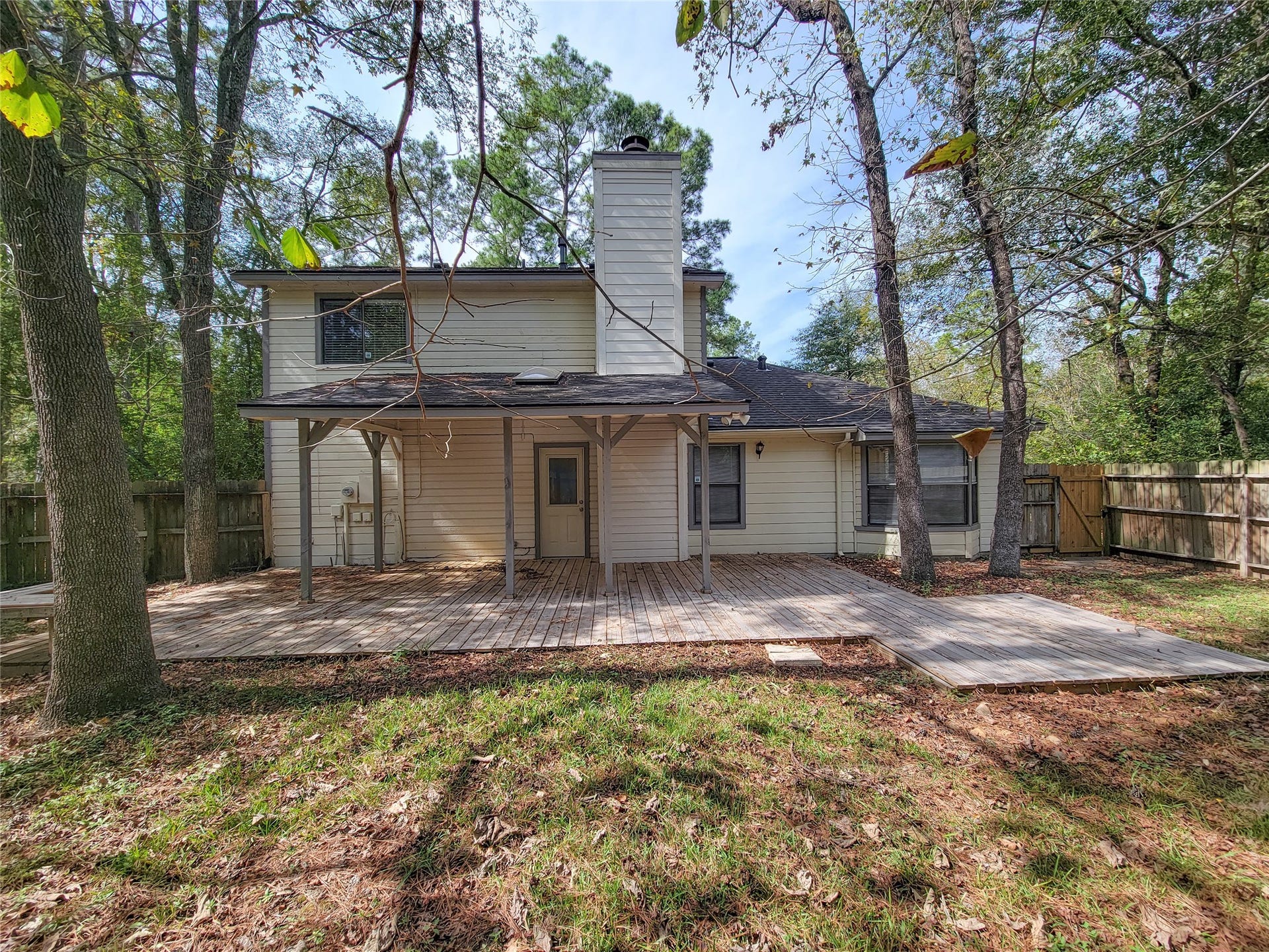80 Fallenstone Drive, The Woodlands, TX 77381 Charming two-story home with a spacious wooden deck, nestled in a serene wooded backyard, perfect for outdoor gatherings and relaxation.