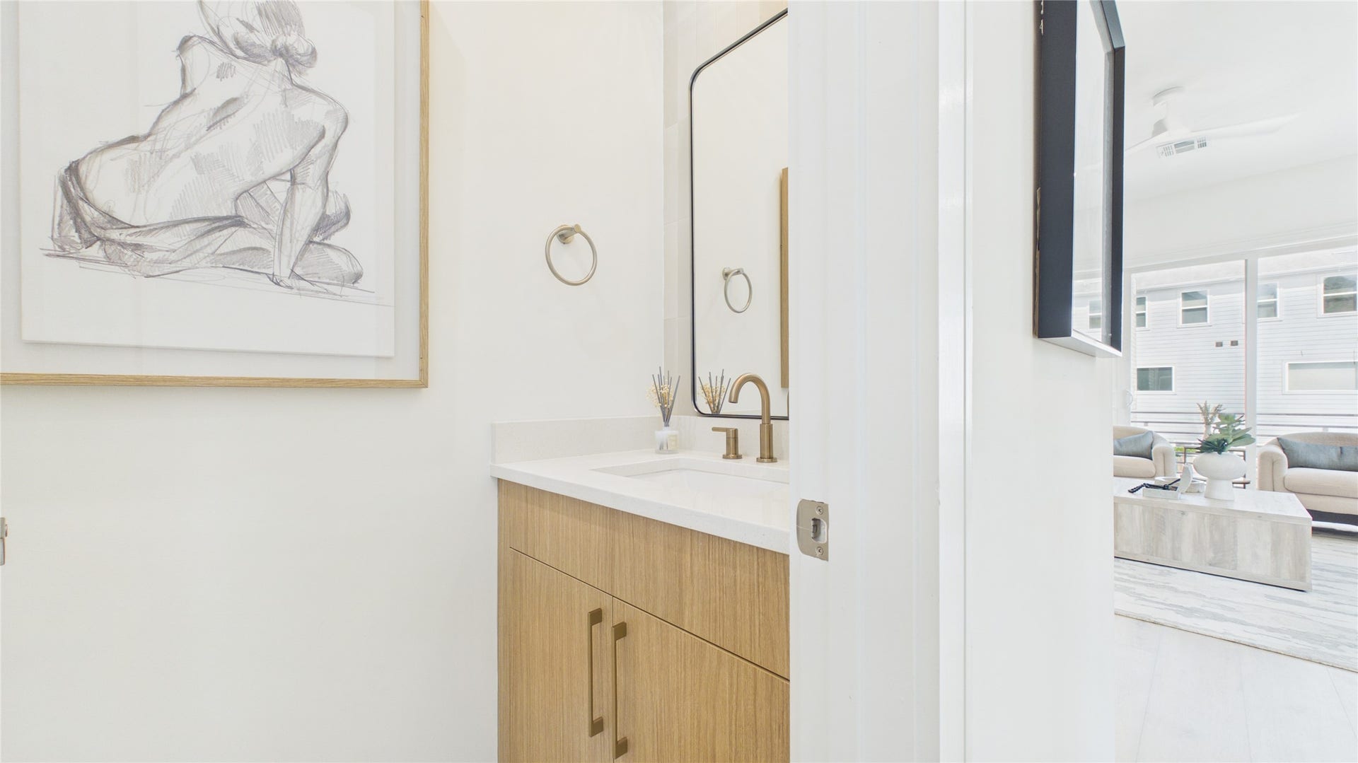Modern half bathroom features a sleek wooden vanity with brass fixtures. Located on the second floor away from the kitchen.