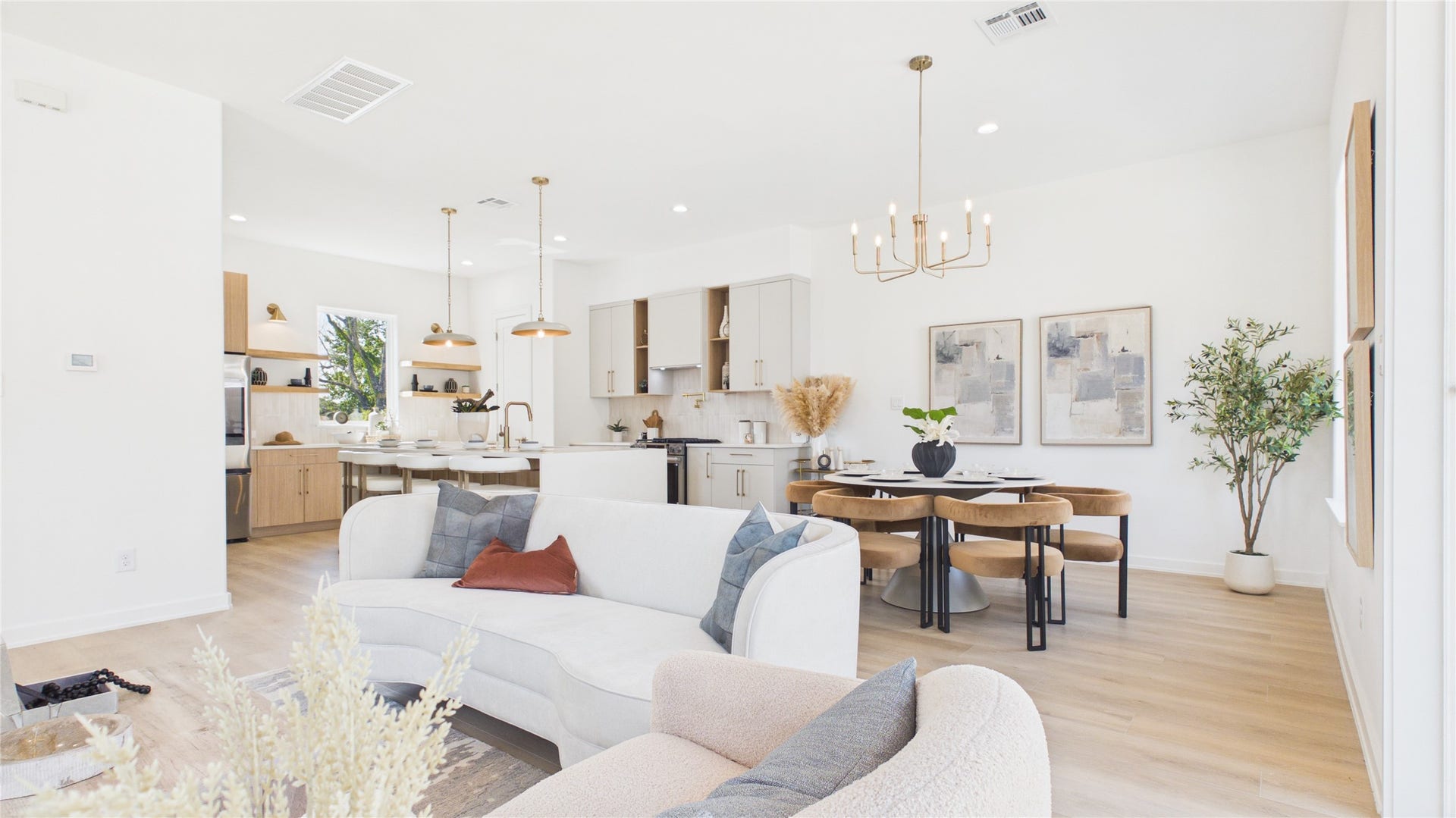 Bright and airy open-concept living area with modern kitchen, elegant dining space, and cozy seating, featuring sleek finishes and warm wood accents.