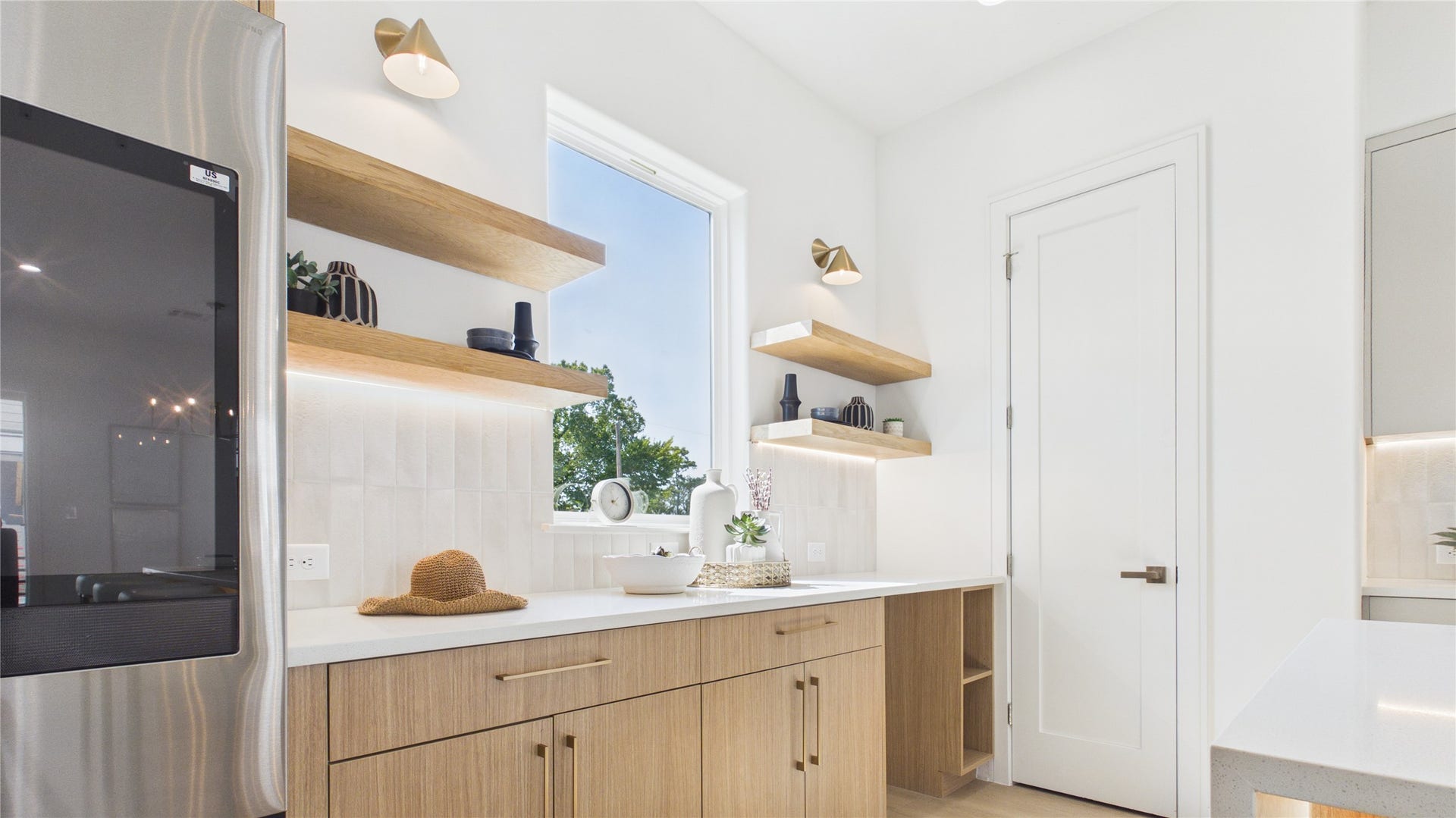 Plenty of counter space with open shelving, and custom cabinetry, all illuminated by contemporary wall sconces and under cabinet lighting.