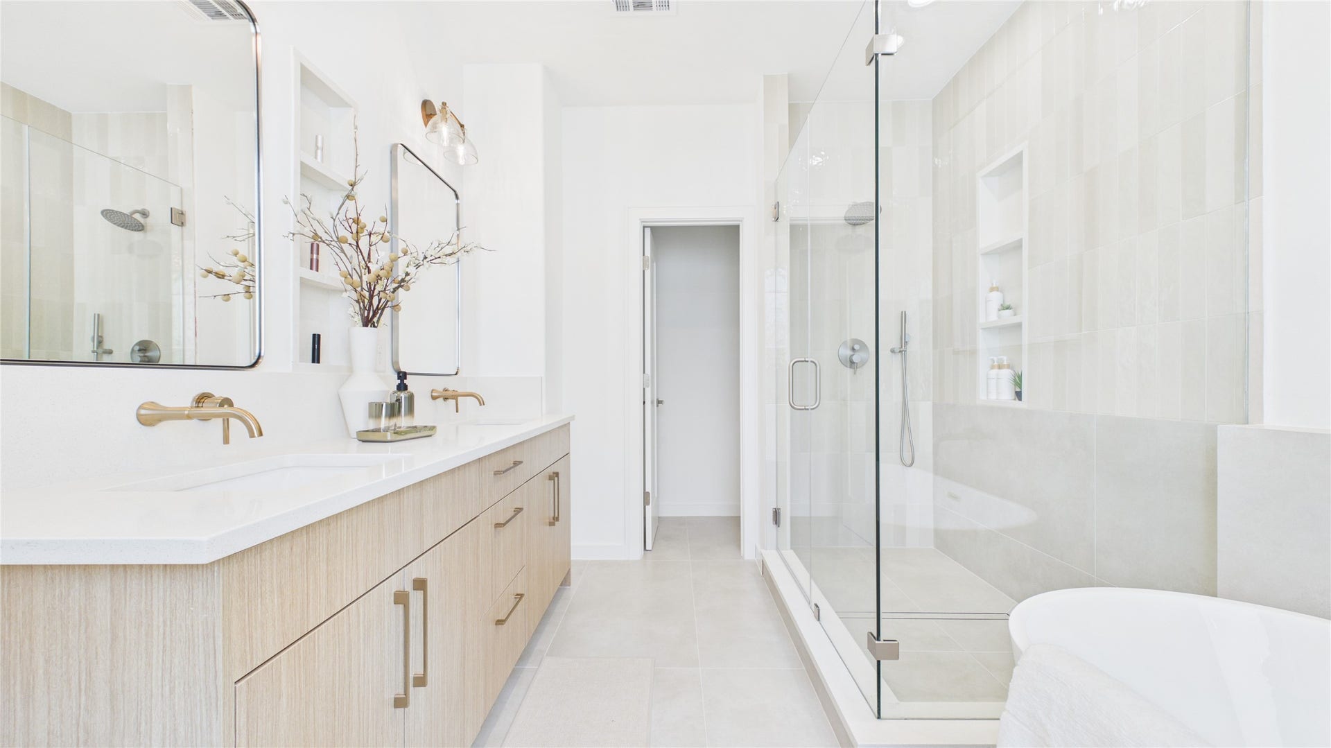 Bright and luxurious bathroom featuring a double vanity with elegant fixtures, and quartz niches.
