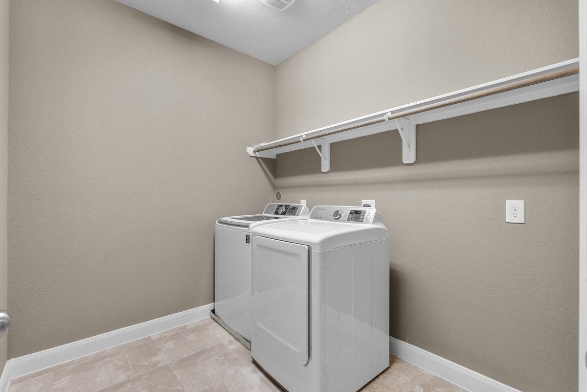 416 Via Regatta Drive, Webster, TX 77598 This spacious utility room features low-maintenance tile flooring, neutral walls with crisp white baseboards, and plenty of functional footprint for sorting and folding. A long, built-in upper storage shelf and heavy-duty hanging rod provide the perfect setup for organizing laundry supplies and air-drying garments right out of the wash.