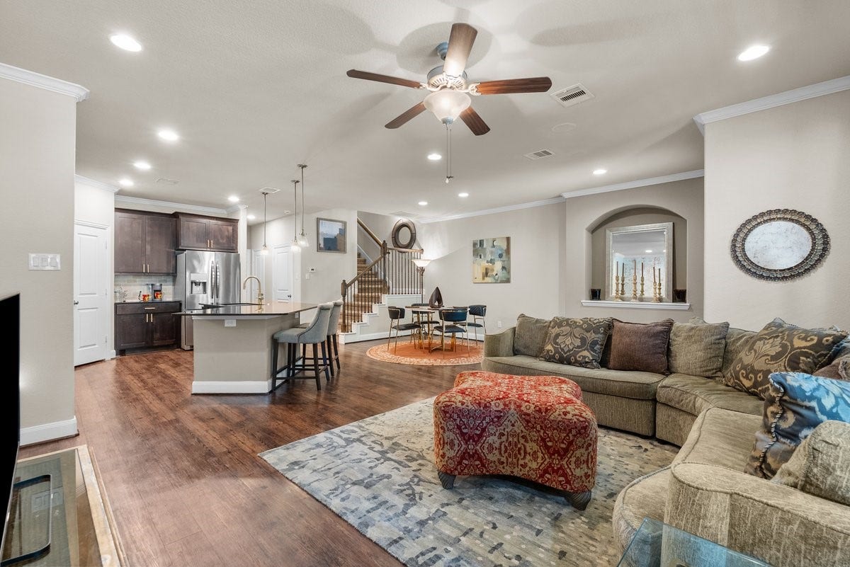 416 Via Regatta Drive, Webster, TX 77598 Rich wood floors flow seamlessly beneath a bright ceiling detailed with elegant crown molding, a central ceiling fan, and abundant recessed lighting.