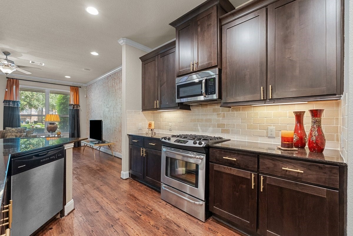 416 Via Regatta Drive, Webster, TX 77598 The gourmet kitchen is a chef's dream, featuring a massive wrap-around island breakfast bar, elegant dark wood cabinetry, stainless steel appliances, and stylish pendant lights.