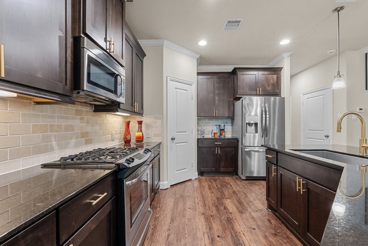416 Via Regatta Drive, Webster, TX 77598 Gourmet Kitchen with Rich Hardwood Flooring, Island Sink with Gold Faucet, Stainless Steel Appliances, Butler Pantry & Coffee Nook.