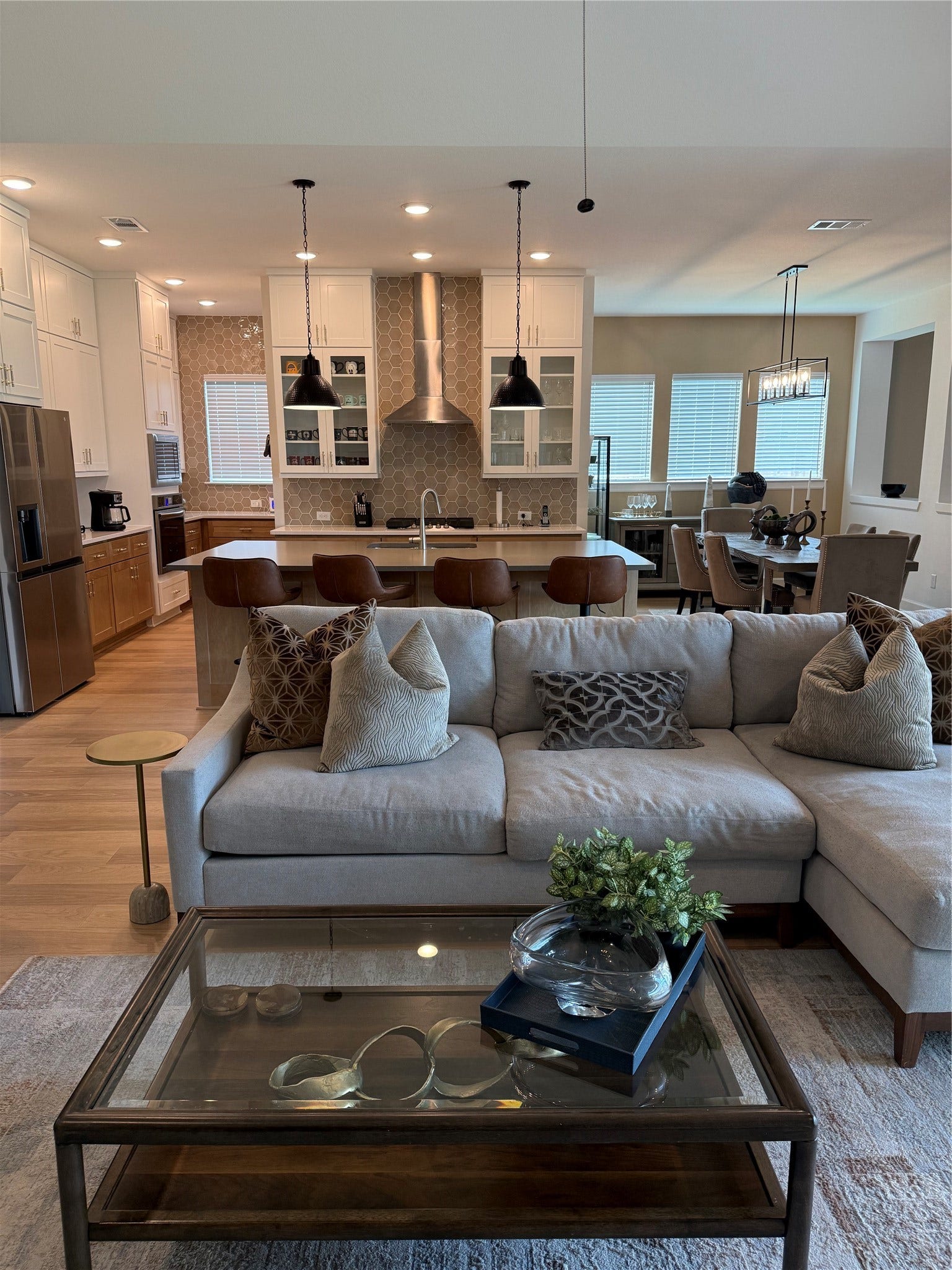 9911 Deep Water Drive, Missouri City, TX 77459 Open-concept living area featuring a modern kitchen with a extended island, pendant lighting, and stainless steel appliances, seamlessly flowing into a cozy living space with a plush sofa and stylish decor and dining area.